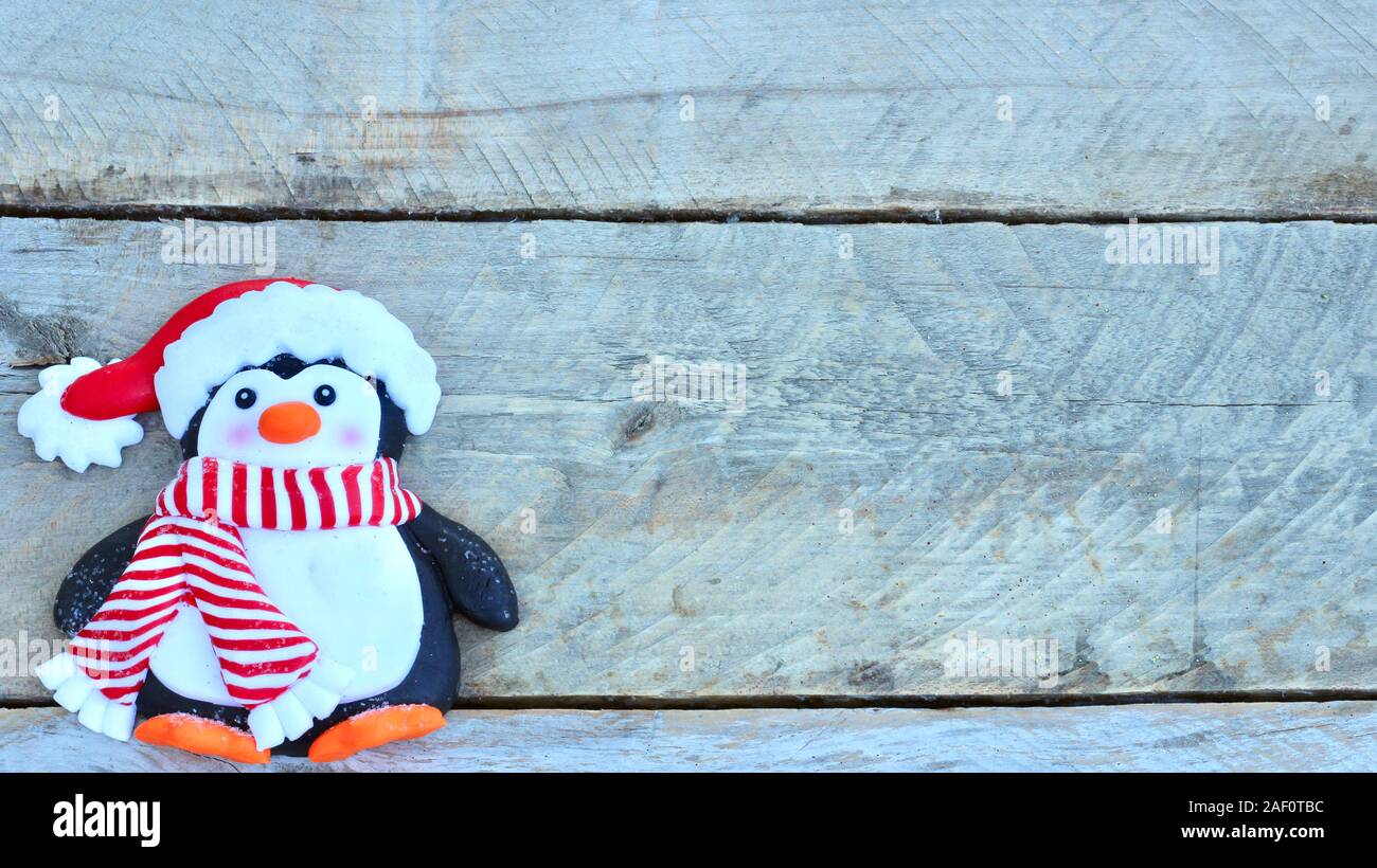 Pinguin mit Santa Claus hat, gestreiften roten und weißen Schal, und orange Füße flach auf natürliche Holz Hintergrund mit Kopie Raum Stockfoto