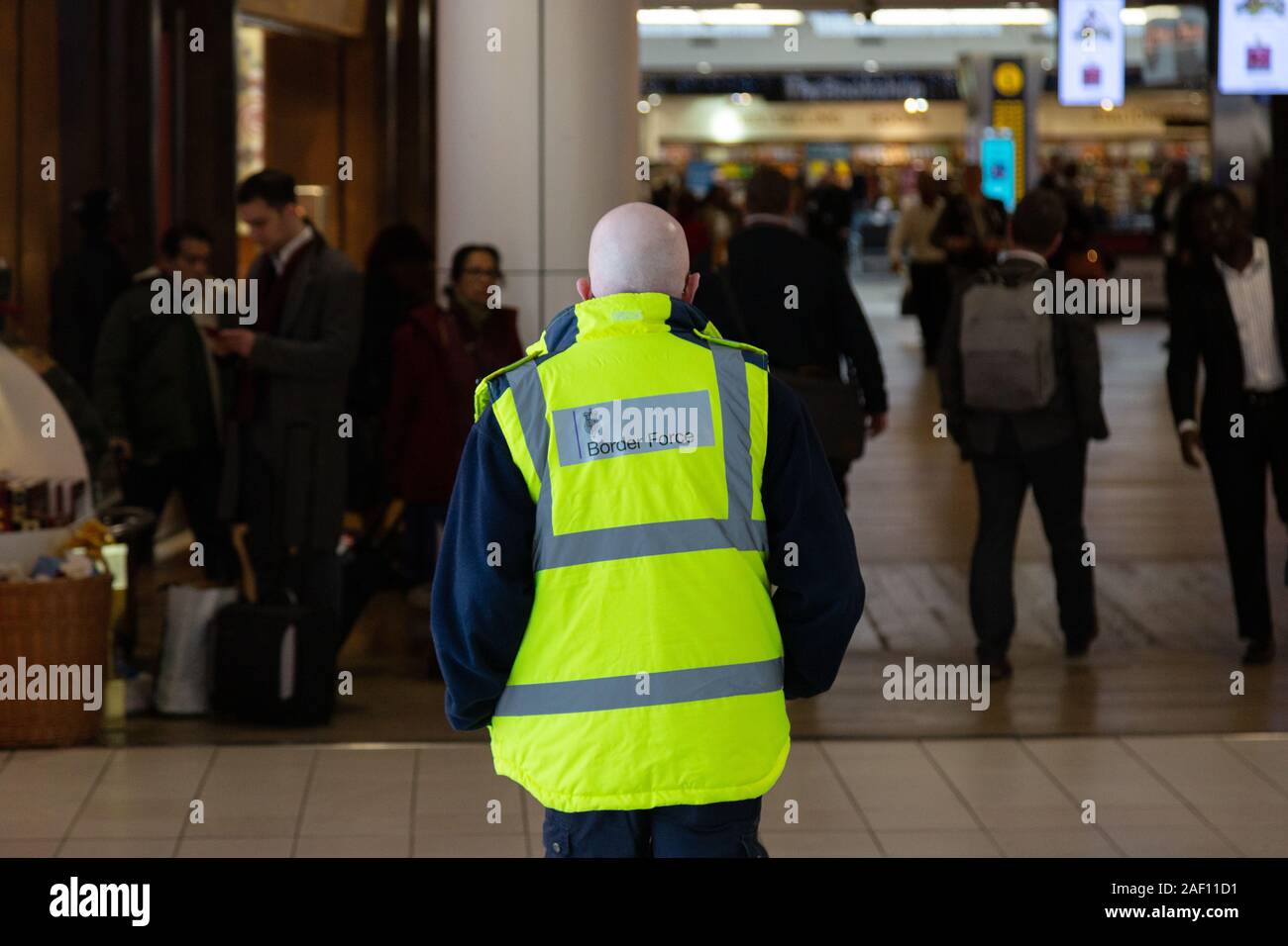 Britischer Grenzkontrollbeamter; britisches Grenzschutzpersonal, das in T3, Flughafen Heathrow, Rückansicht, Flughafen London, Großbritannien arbeitet. Britische Arbeitskraft. Stockfoto