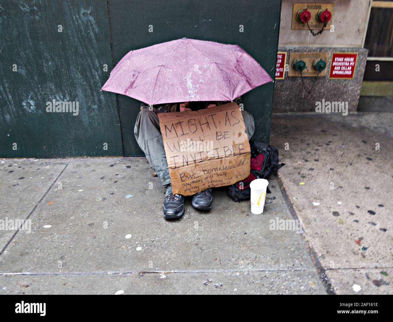 Obdachloser Mann um Geld betteln im Regen am Times Square in New York City Stockfoto