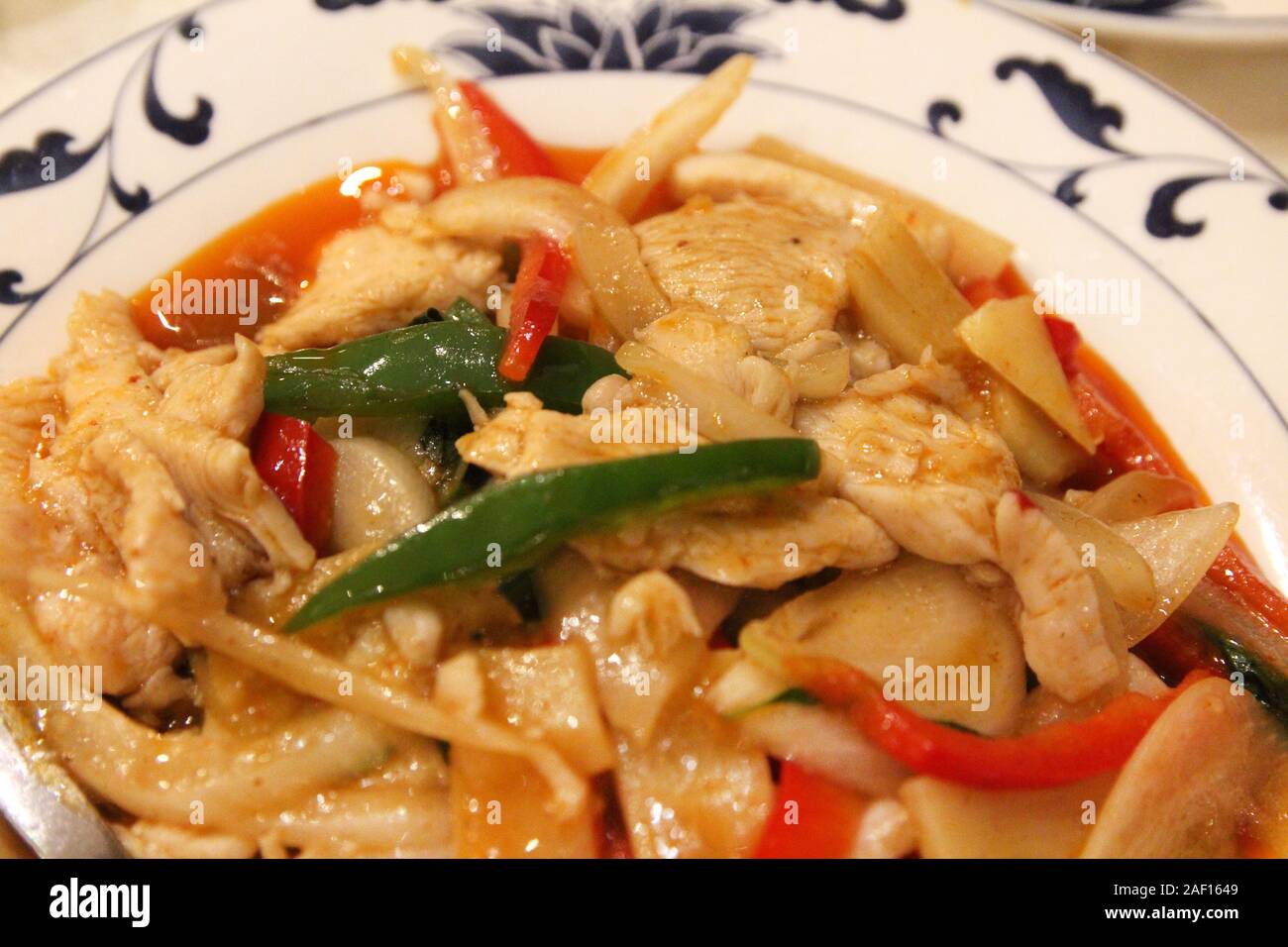 Gebratenes Huhn mit Chiliphrern und Zwiebeln in Soße in einem chinesischen Restaurant umrühren Stockfoto