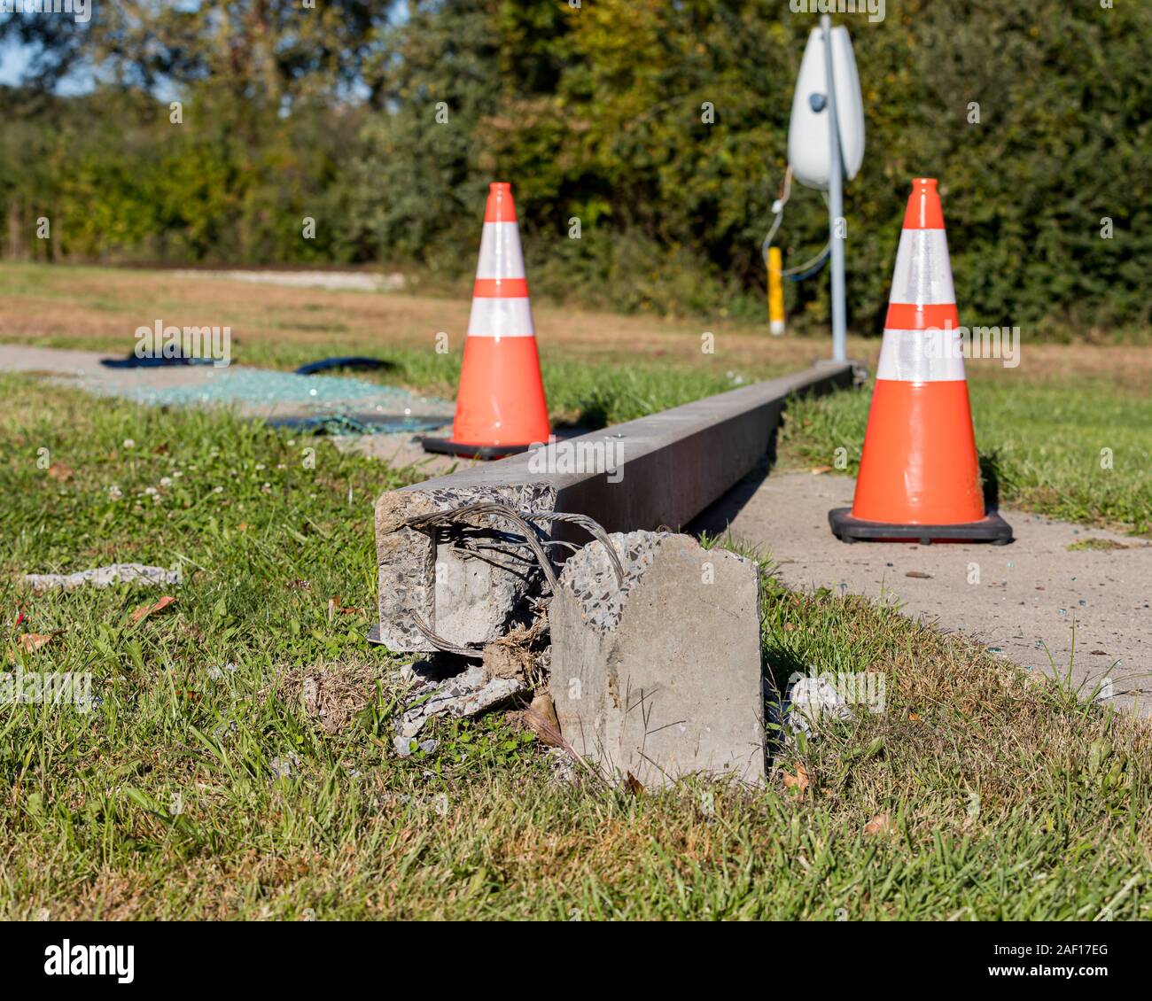 Konkrete streetlight Pol von Autounfall mit freiliegenden Drähte gebrochen und Festlegung über Bürgersteig. orange Leitkegel, Shattered Glas im Hintergrund Stockfoto
