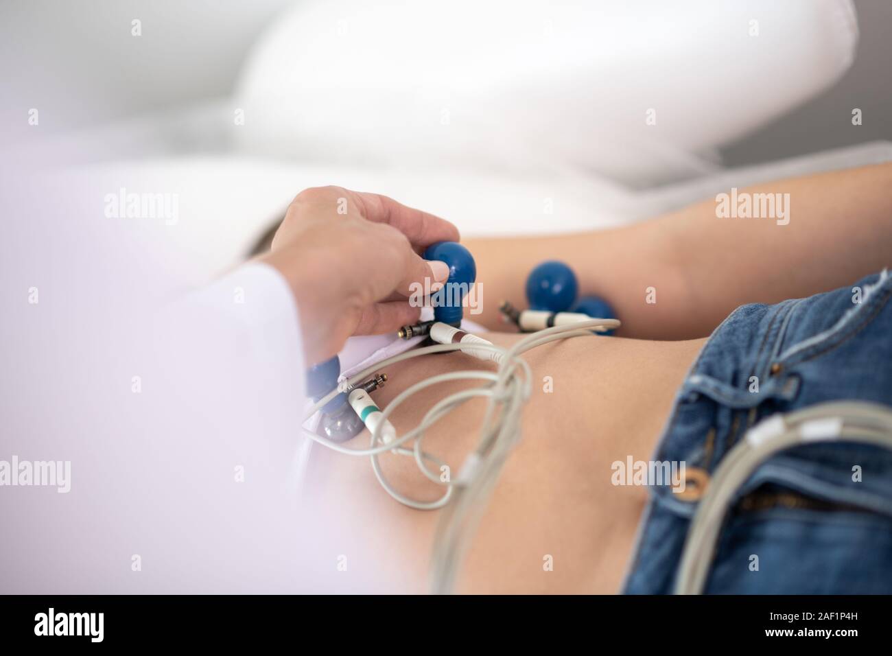 Arzt im weißen Gewand electrodiods befestigen Sie sie an den Patienten Brust Stockfoto