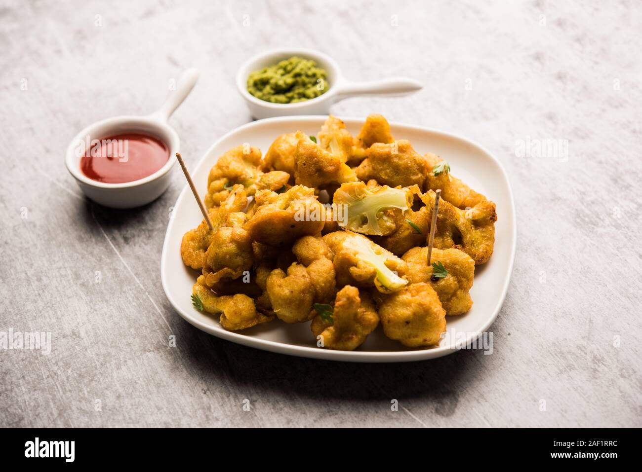 Gobi Pakora oder Phoolgobi Pakoda aus frischem Blumenkohl getauchten Kichererbsen Teig und dann in Öl gebraten. Serviert mit Tomatenketchup und Minze Chutney Stockfoto