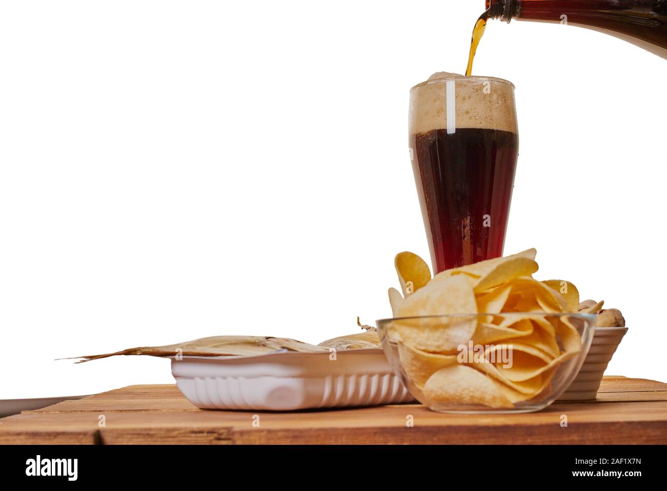 Bier ist in ein Glas mit einem Imbiss auf den Tisch schüttete Stockfoto