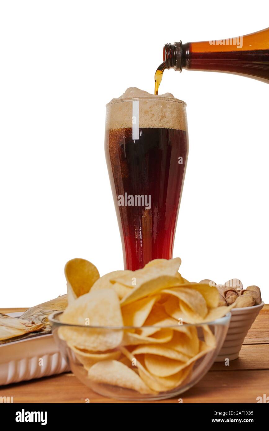 Bier ist in ein Glas mit einem Imbiss auf den Tisch schüttete Stockfoto