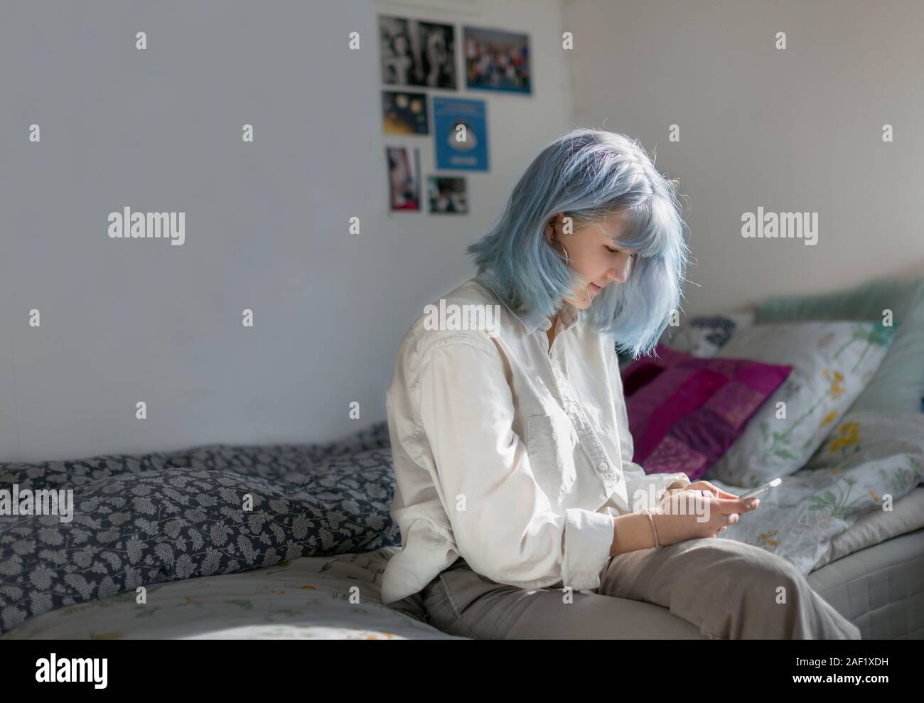 Junge Frau mit Handy im Schlafzimmer Stockfoto