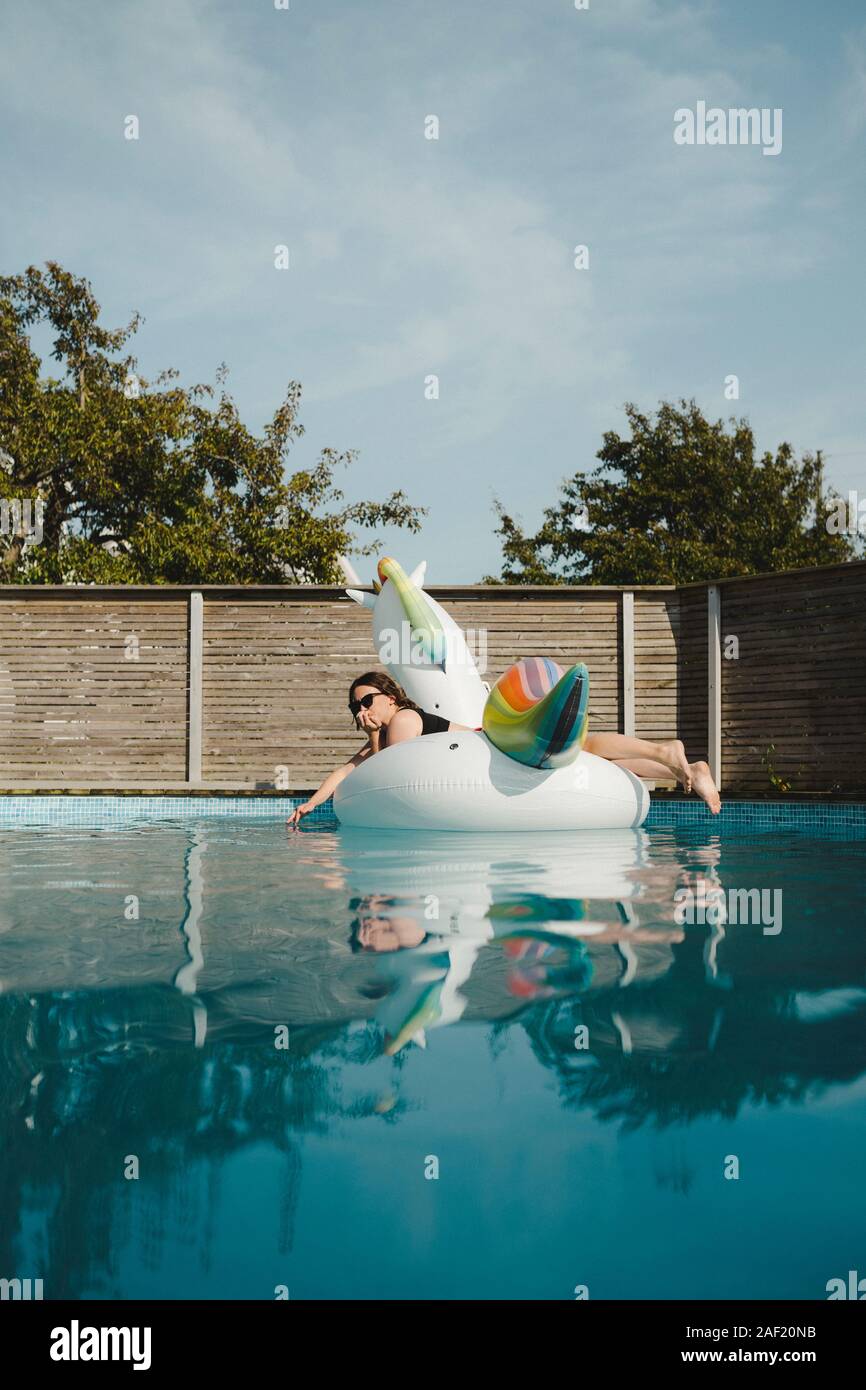 Frau auf aufblasbaren Einhorn in den Swimming-pool Stockfoto