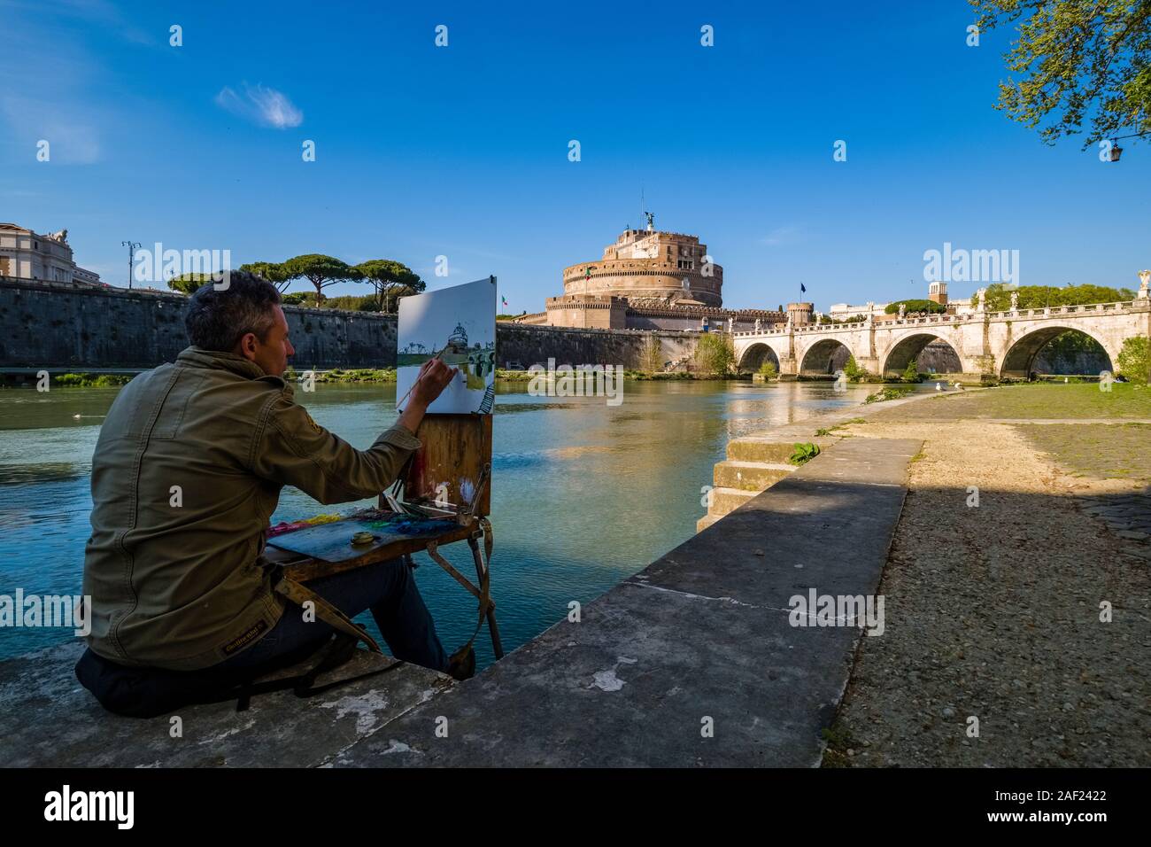 Ein Künstler malt das Schloss der Heiligen Engel, Castel Sant'Angelo und der Brücke Ponte Sant'Angelo, über den Fluss Tiber gesehen Stockfoto