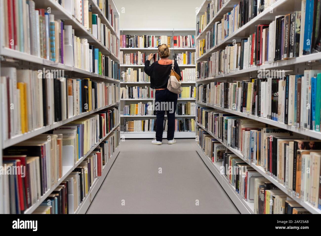 Innenraum der Guilherand Granges Multimedia Bibliothek in der Ardèche (Frankreich). Die Frau in der Nähe der Römischen Regale Stockfoto