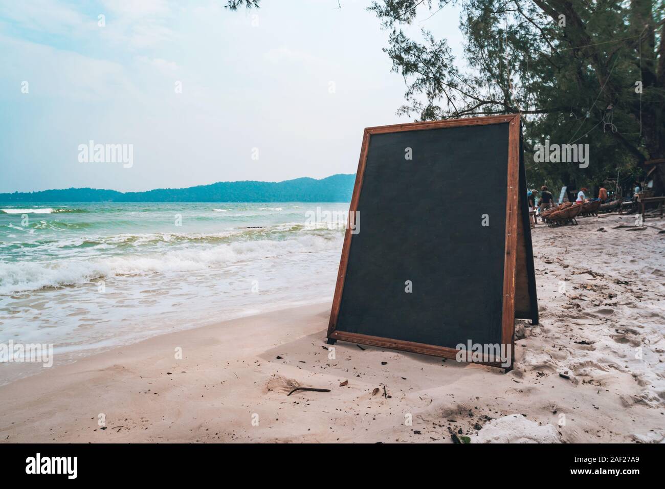 Leere holzschild am Strand. Schwarzes Brett für das Schreiben im Menü Chalk auf weißem Sand am Strand auf einer tropisch-exotischen Insel. Stockfoto