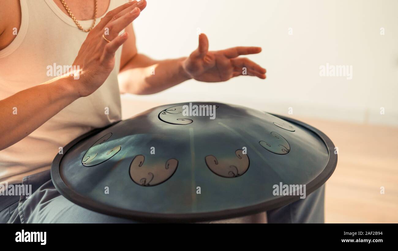 Nahaufnahme des Menschen Hände spielen Hang Drum im Innenbereich. Ungewöhnliche Musik Instrument. Konzept der Sound für die Meditation Stockfoto