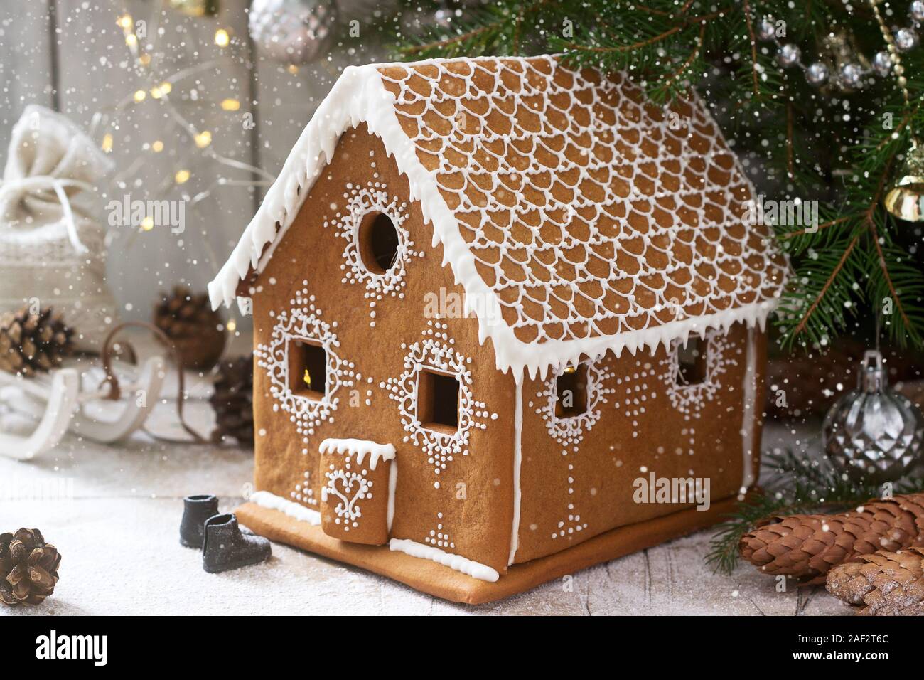 Lebkuchenhaus und Weihnachtsbäume auf einen hellen Hintergrund. Bokeh Wirkung. Stockfoto