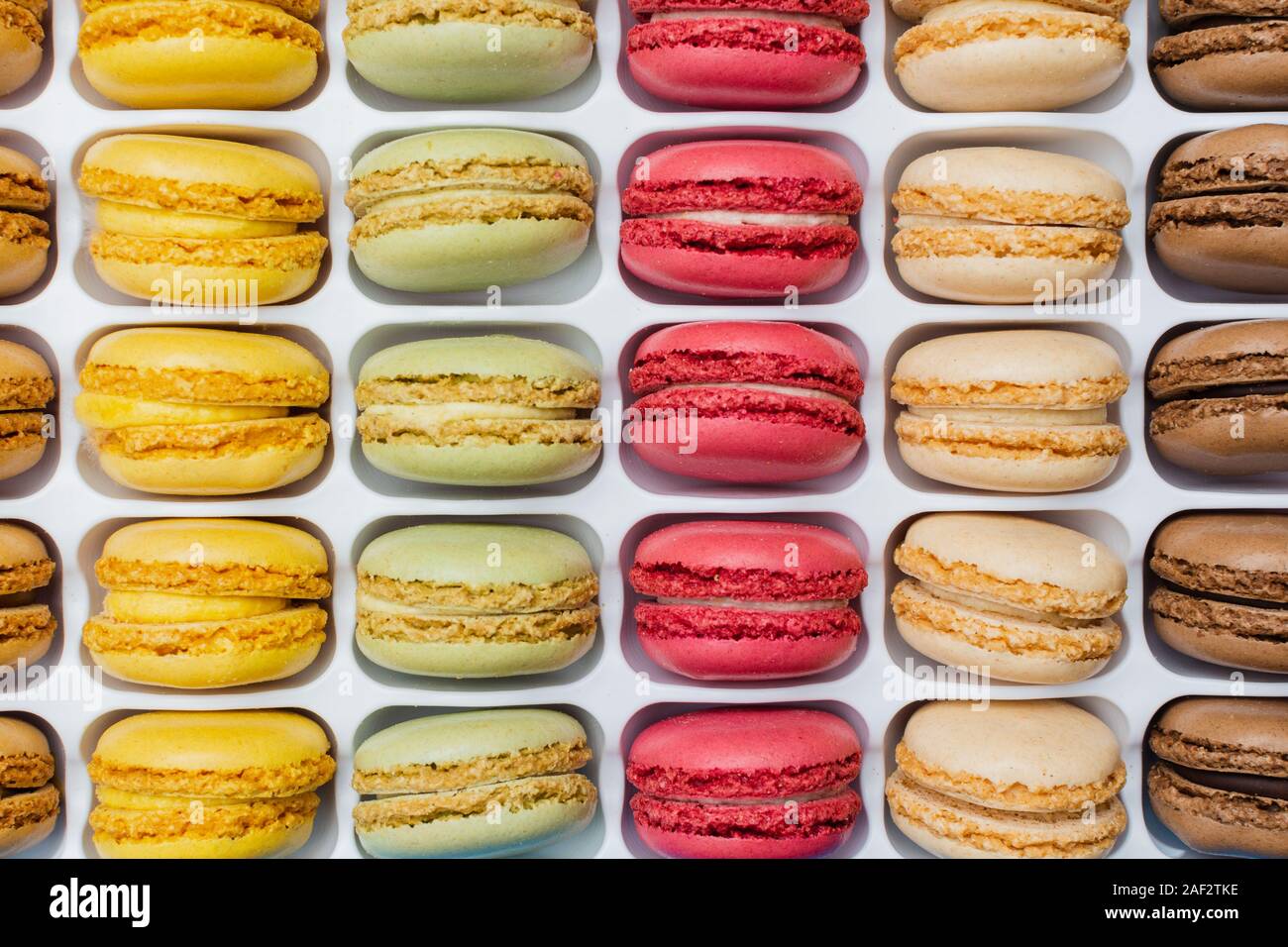 Klassische französische Dessert. Bunte macarons in hellem rosa grün gelb Creme Schokolade in einer Kiste gestapelt, selektiver Fokus Stockfoto