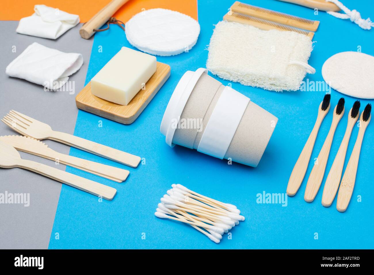 Null Abfall umweltfreundliche Personal Care Produkte bambus holz- Bürsten, Zahnbürsten, luffa, Naturseifen, wiederverwendbare Kaffeetasse auf bunten Blau Grau orange Hintergrund, selektiver Fokus Stockfoto