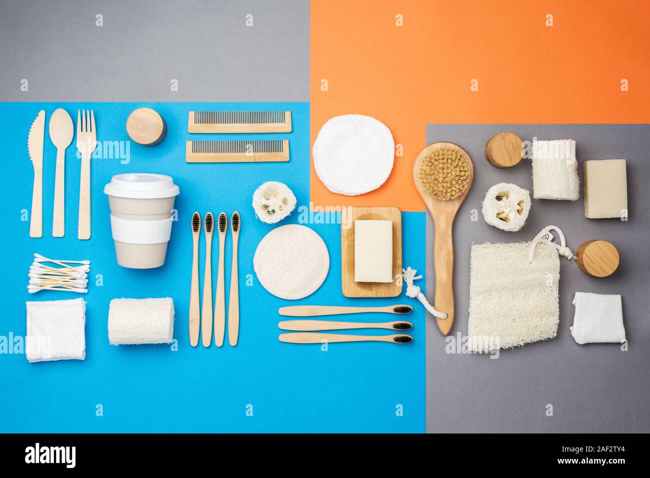 Null Abfall umweltfreundliche Personal Care Produkte bambus holz- Bürsten, Zahnbürsten, luffa, Naturseifen, wiederverwendbare Kaffeetasse auf bunten Blau Grau orange Hintergrund, selektiver Fokus Stockfoto
