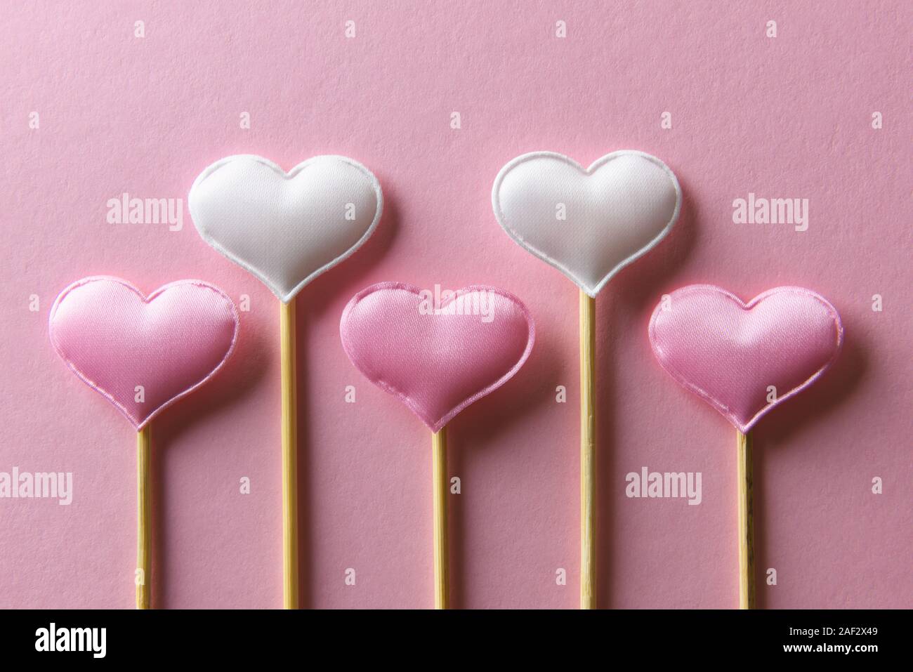 Rosa textile Herzen auf Holzstäbchen Nahaufnahme. Valentines Tag Hintergrund, kreative Textur und liebe Konzept Stockfoto