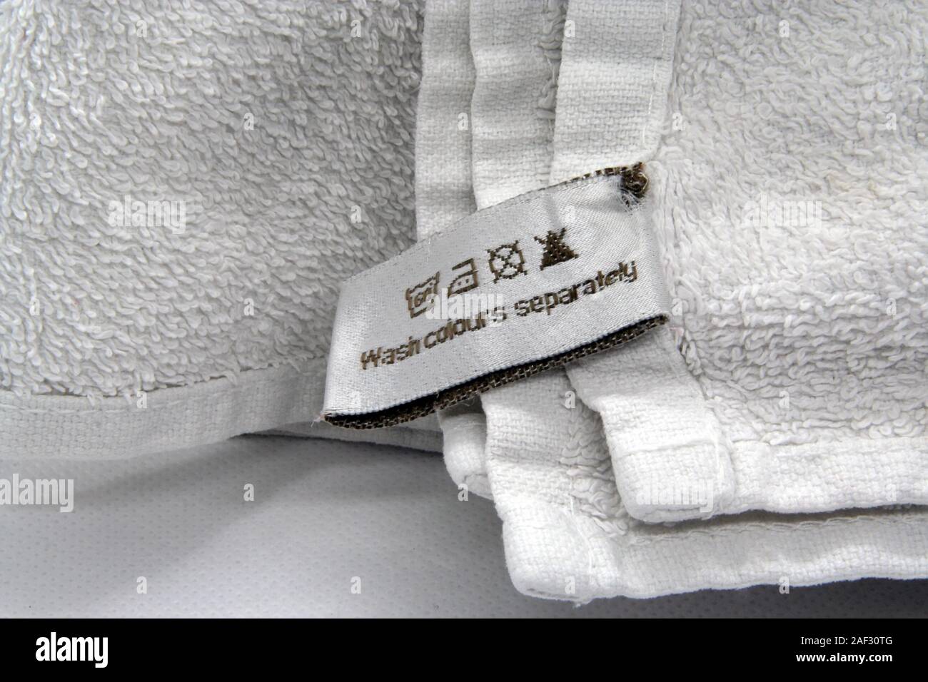 Waschanleitung Kleidung Aufkleber auf weisser Baumwolle als Hintergrund. Weiße Handtücher im Badezimmer. Stockfoto