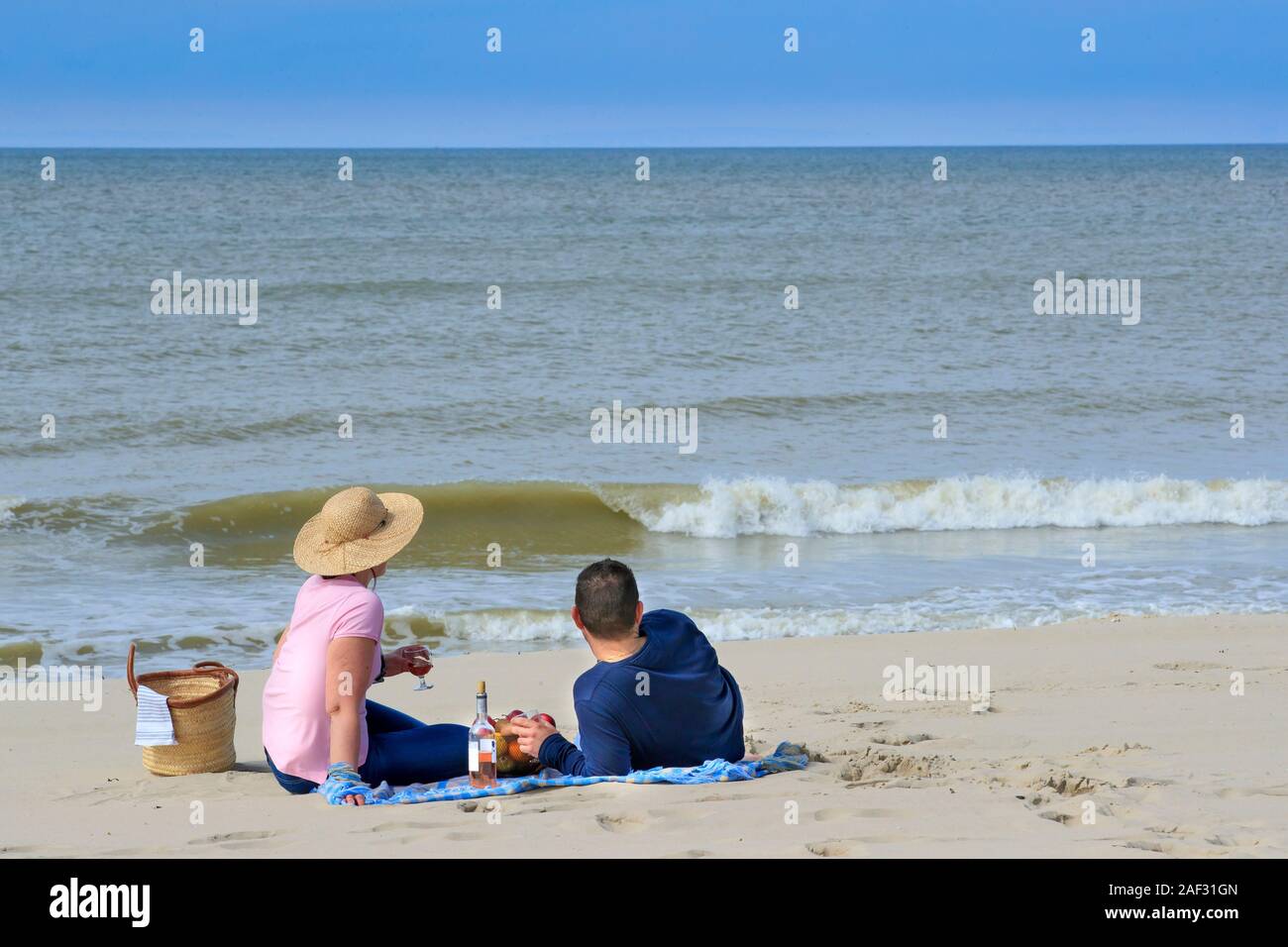 Paar am Strand, mit Blick auf das Meer, mit einem Picknick Stockfoto