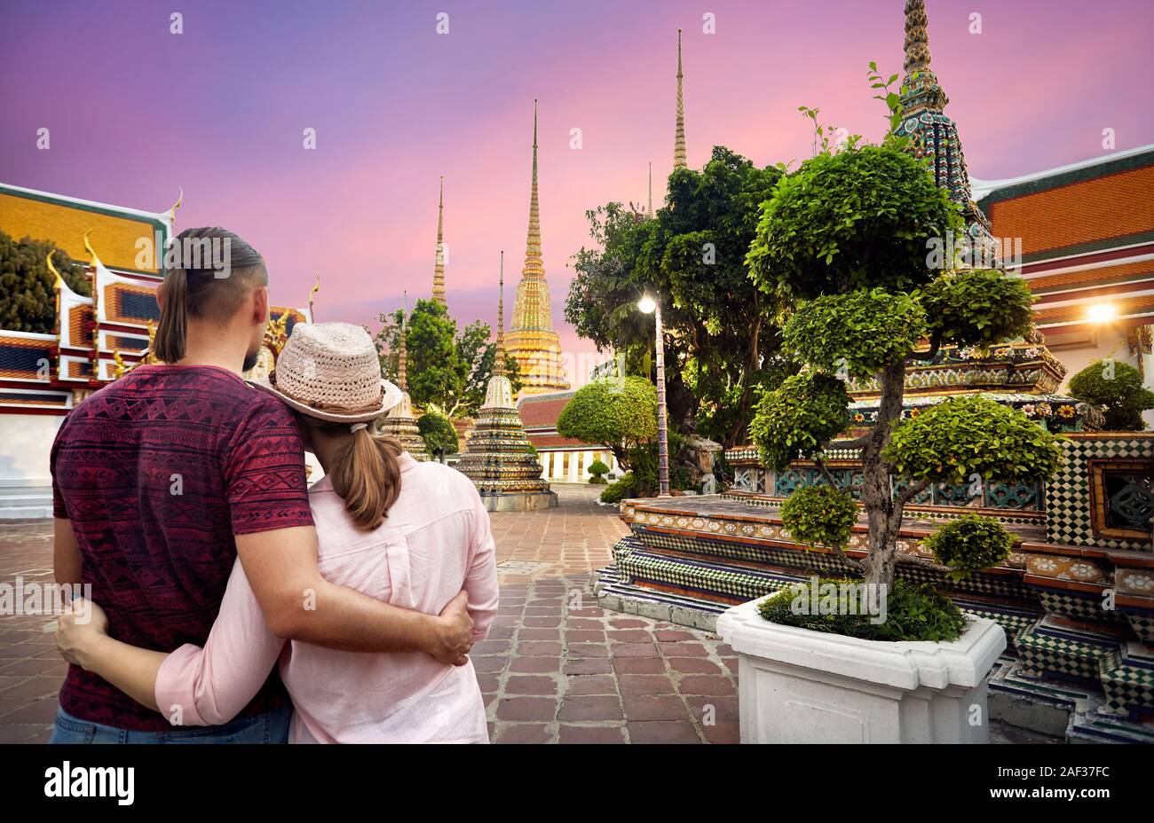 Junge Familie auf der Suche nach Garten von Wat Pho Tempel in lila Probe in Bangkok, Thailand Stockfoto