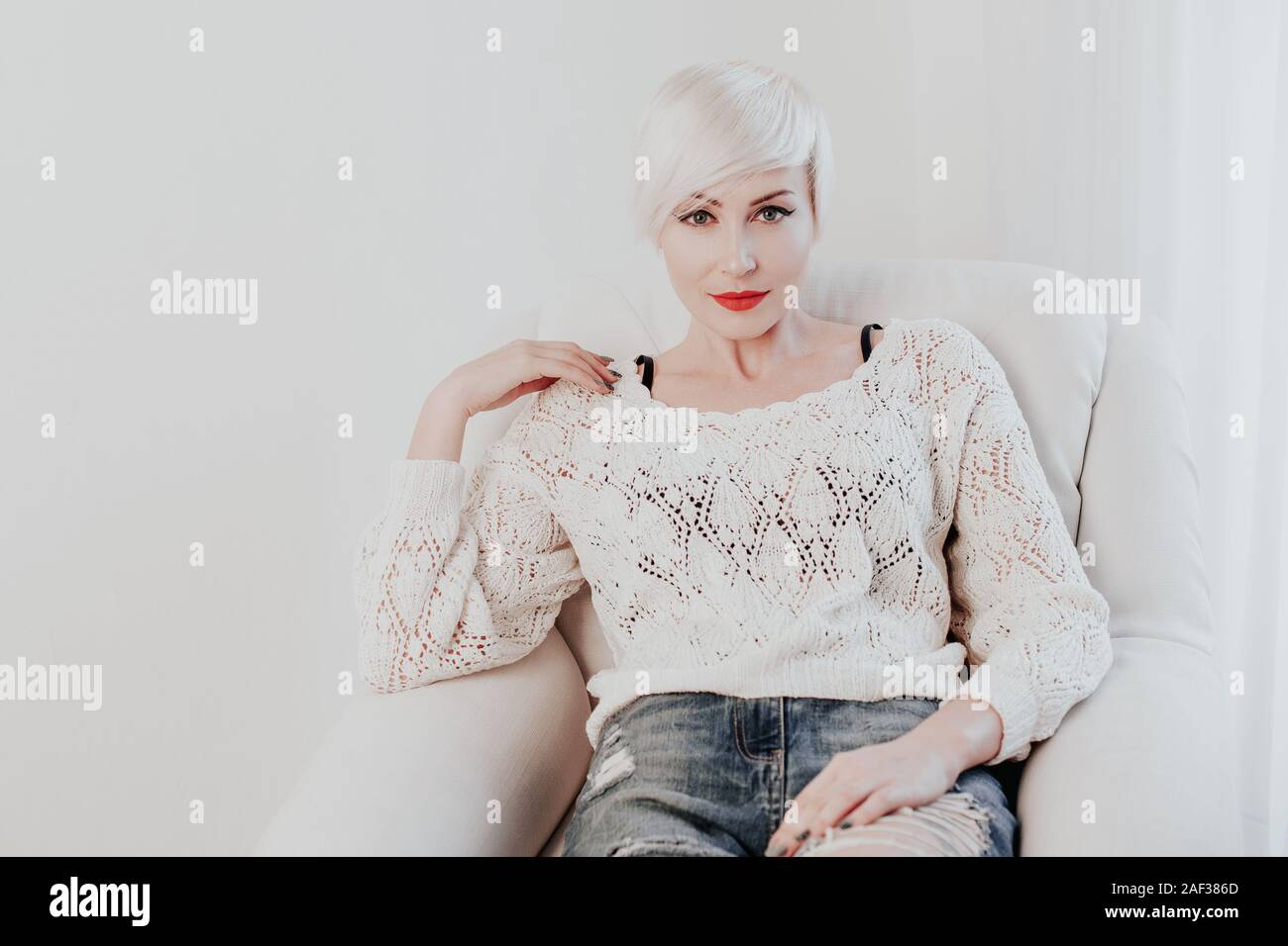 Schöne französische blonde Frau in einem weißen Zimmer Stockfoto