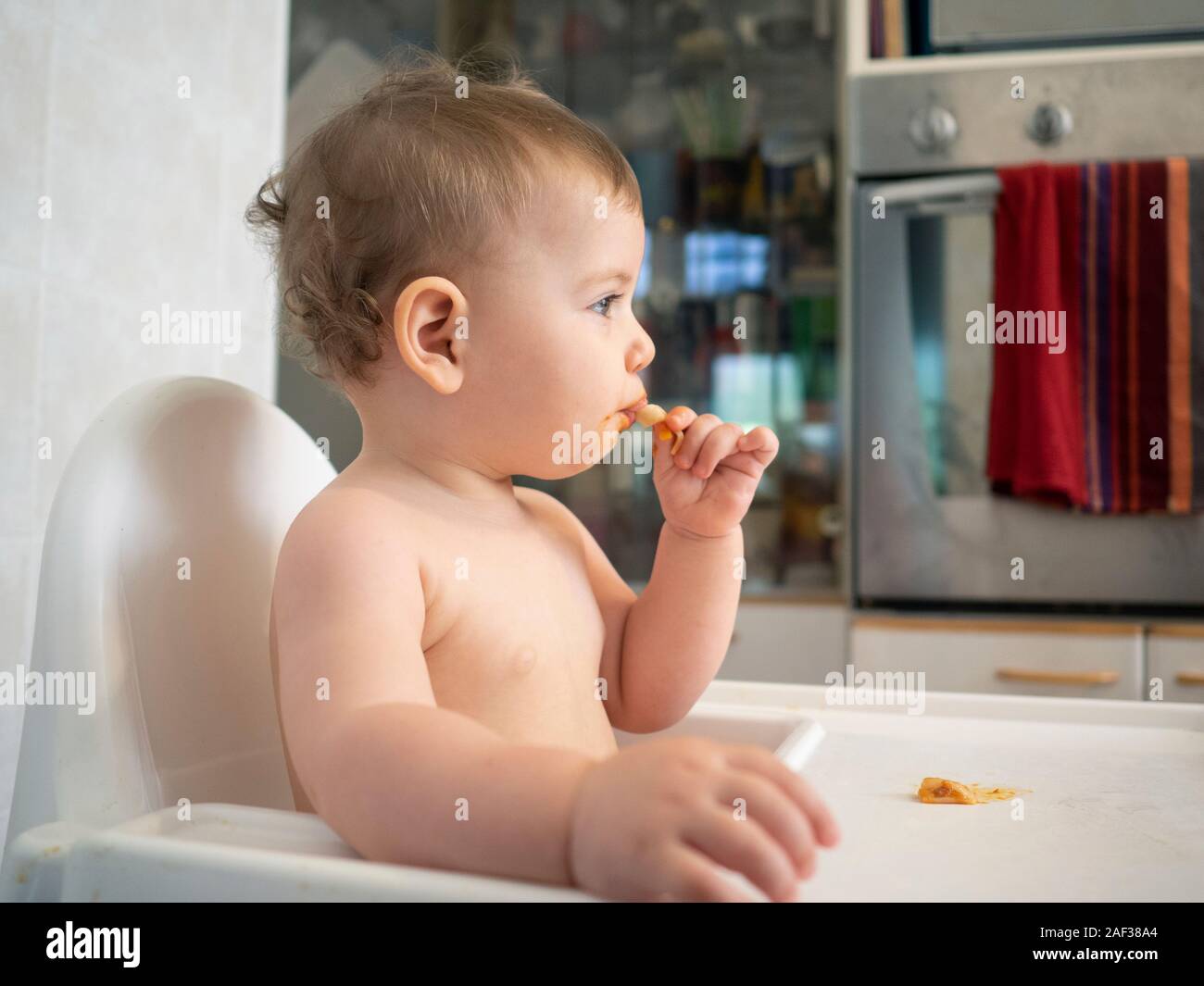 1 Jahr alte Hündin Baby sitzt auf einem hohen Stuhl warten auf Ihre Mahlzeit Stockfoto