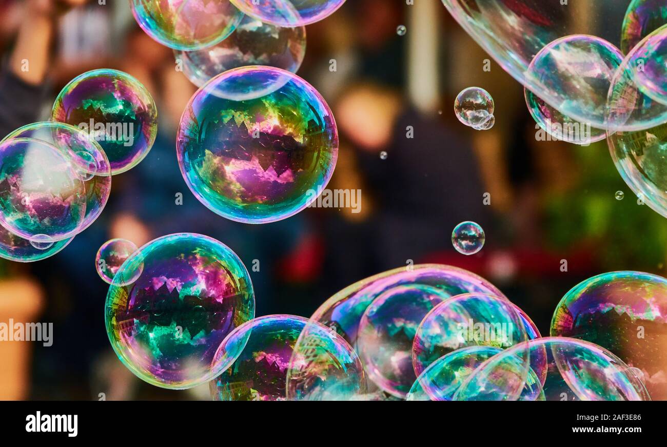 Metallic leuchtende bunte Seifenblasen in die Luft vor einem verschwommenen Abstrakt Hintergrund Stockfoto