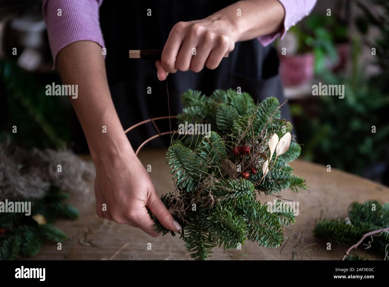 Frau, die Weihnachten Kranz von Fichte, Schritt für Schritt. Konzept der Floristen Arbeiten vor den Weihnachtsferien. Stockfoto