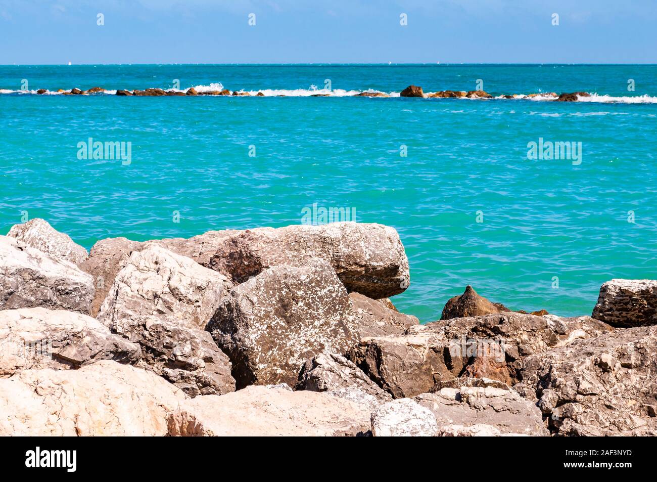 Steine und Felsen am Strand liegen als Grenze zwischen Kiesel Strand Spiaggia del Frate und Adria Wellen und Strömungen. Rocky Marina als breakw Stockfoto