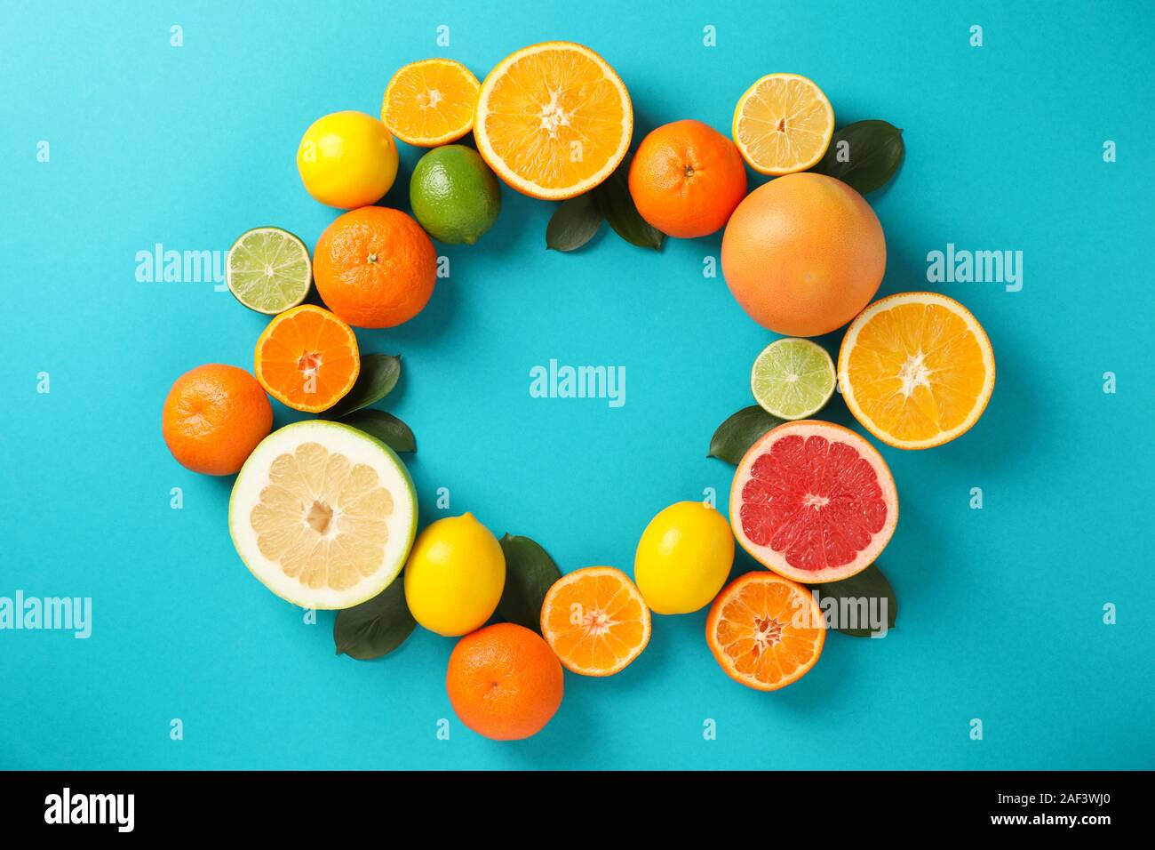 Kreis der saftigen Zitrusfrüchte auf Türkisfarbenem Hintergrund, Platz für Text Stockfoto
