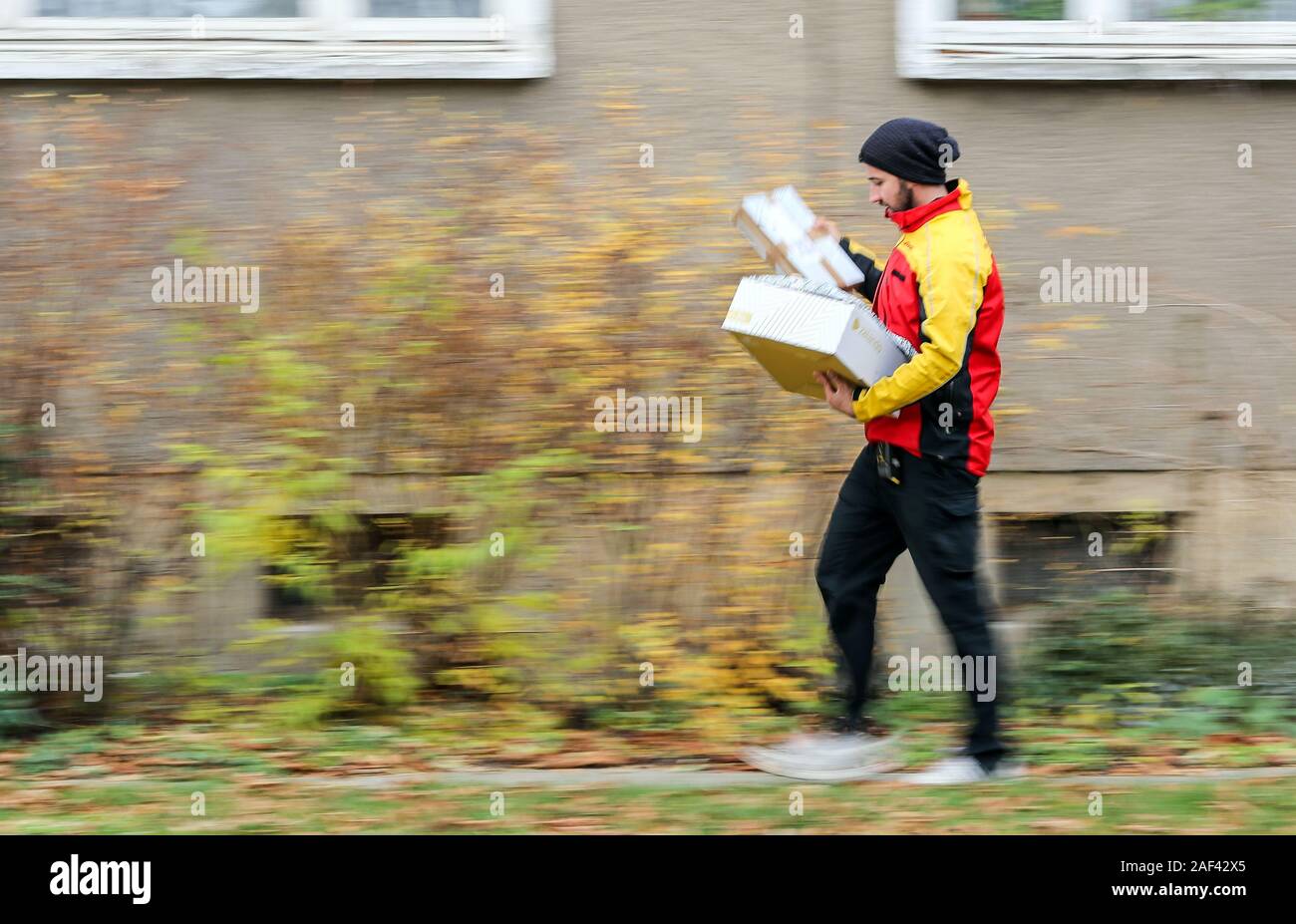 Halle, Deutschland. 11 Dez, 2019. Ein DHL Paketdienst liefert mehrere Sendungen zu einem Haus in der Paulus Bezirk. DHL erwartet einen neuen Datensatz Anzahl der Pakete für die Tage vor Weihnachten. 11 Millionen Pakete pro Tag erwartet, wobei der Jahresdurchschnitt liegt bei 5 Millionen pro Tag. In Halle in der Weihnachtszeit bedeutet 52.000 Parzellen, die von 90 Lieferung Personal jede Woche an den vorderen Türen geliefert werden. Kredite: Jan Woitas/dpa-Zentralbild/ZB/dpa/Alamy leben Nachrichten Stockfoto