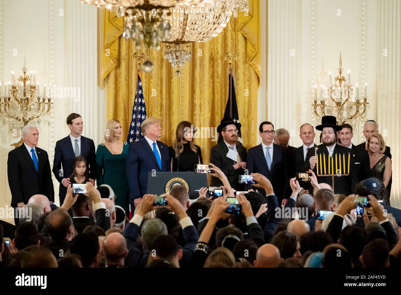 Washington, Vereinigte Staaten von Amerika. 11. Dezember, 2019. Rabbi Moshe Moskowitz leuchtet die Menorah als US-Präsident Donald Trump und First Lady Melania Trump Blick auf während ein Abend Chanukka Empfang im East Room des Weißen Hauses Dezember 11, 2019 in Washington, DC. Credit: D. Myles Cullen/White House Photo/Alamy leben Nachrichten Stockfoto