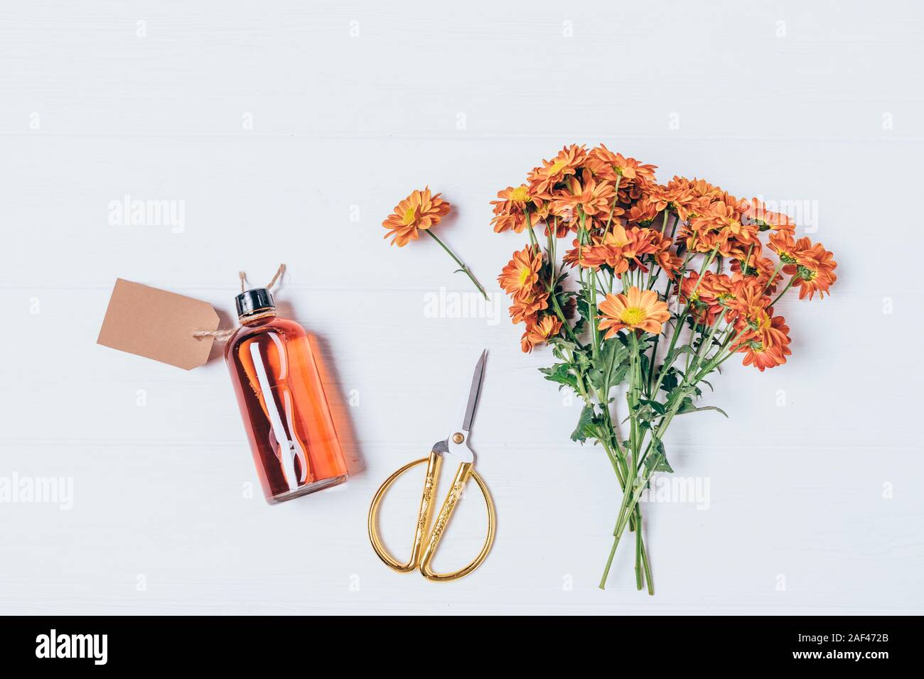 Handgemachte Kosmetik lotion Flasche neben Strauß mit frischen Blumen auf weißem Holz- Tabelle, Ansicht von oben. Stockfoto