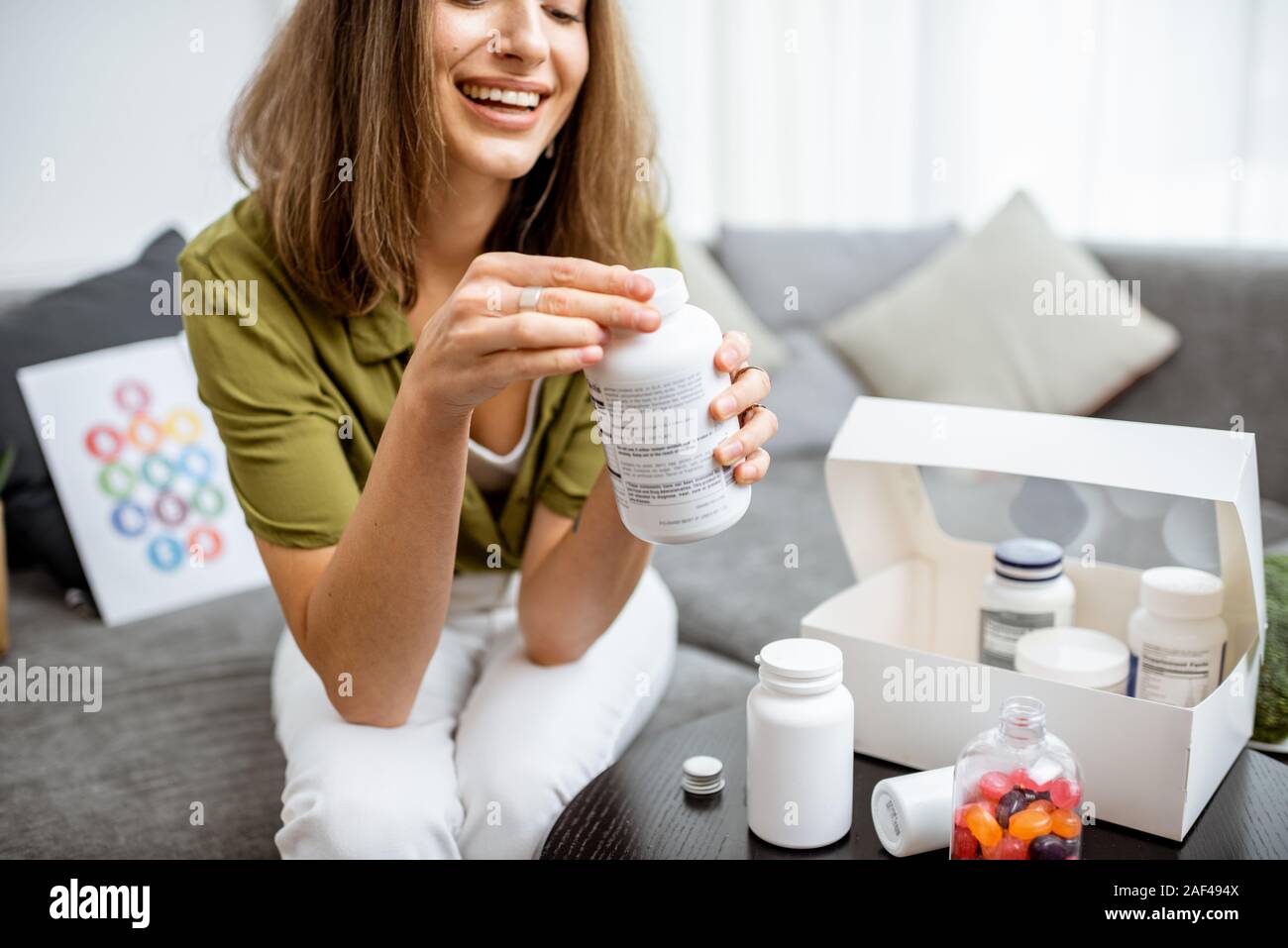 Frau, Vitamine oder Nahrungsergänzungsmittel in Form von Pillen, während auf der Couch zu Hause sitzen. Konzept der biohacking und präventive Medizin Stockfoto