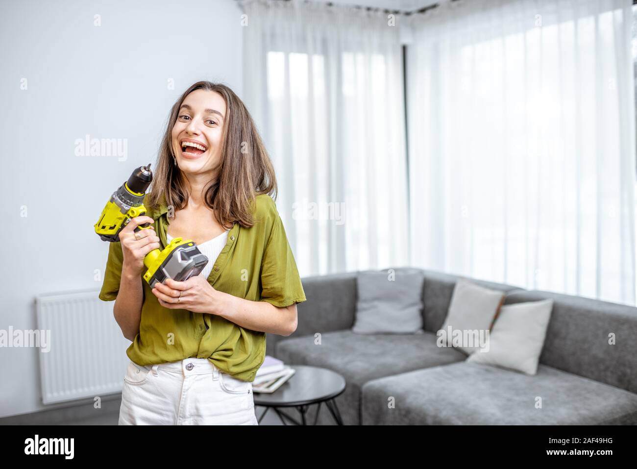 Portrait einer jungen und glücklich handywoman mit Akkuschrauber zu Hause. Konzept eines einfachen Haushalt arbeiten mit modernen Werkzeugen Stockfoto