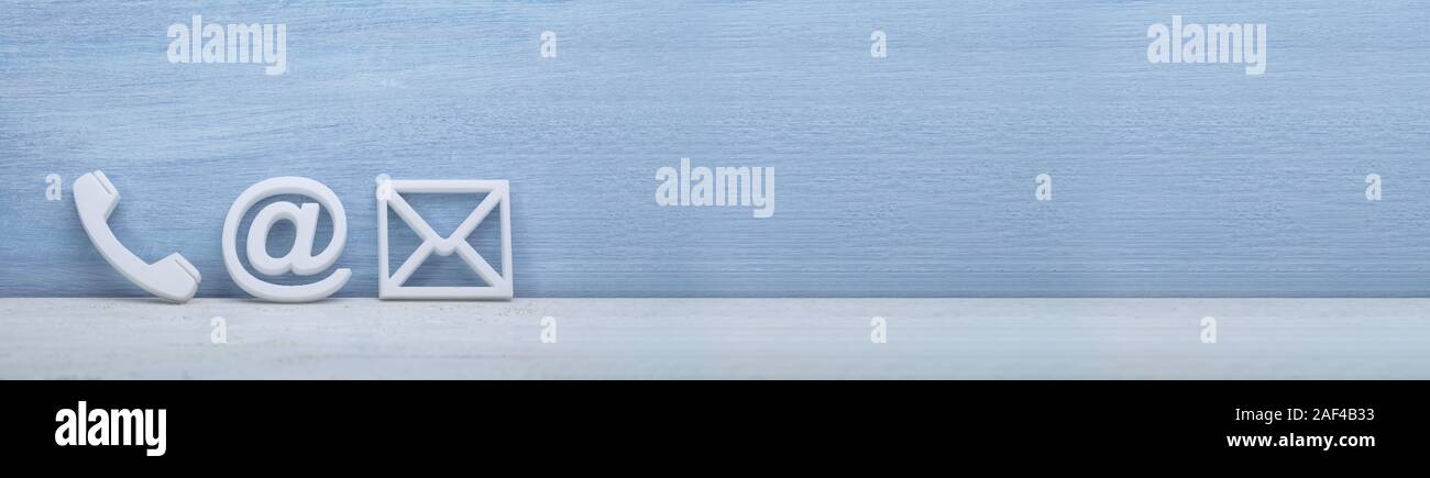 Weiß beliebte Kontakt Web Icons auf dem Schreibtisch über das reflektierende Schreibtisch gegen graue Wand Stockfoto