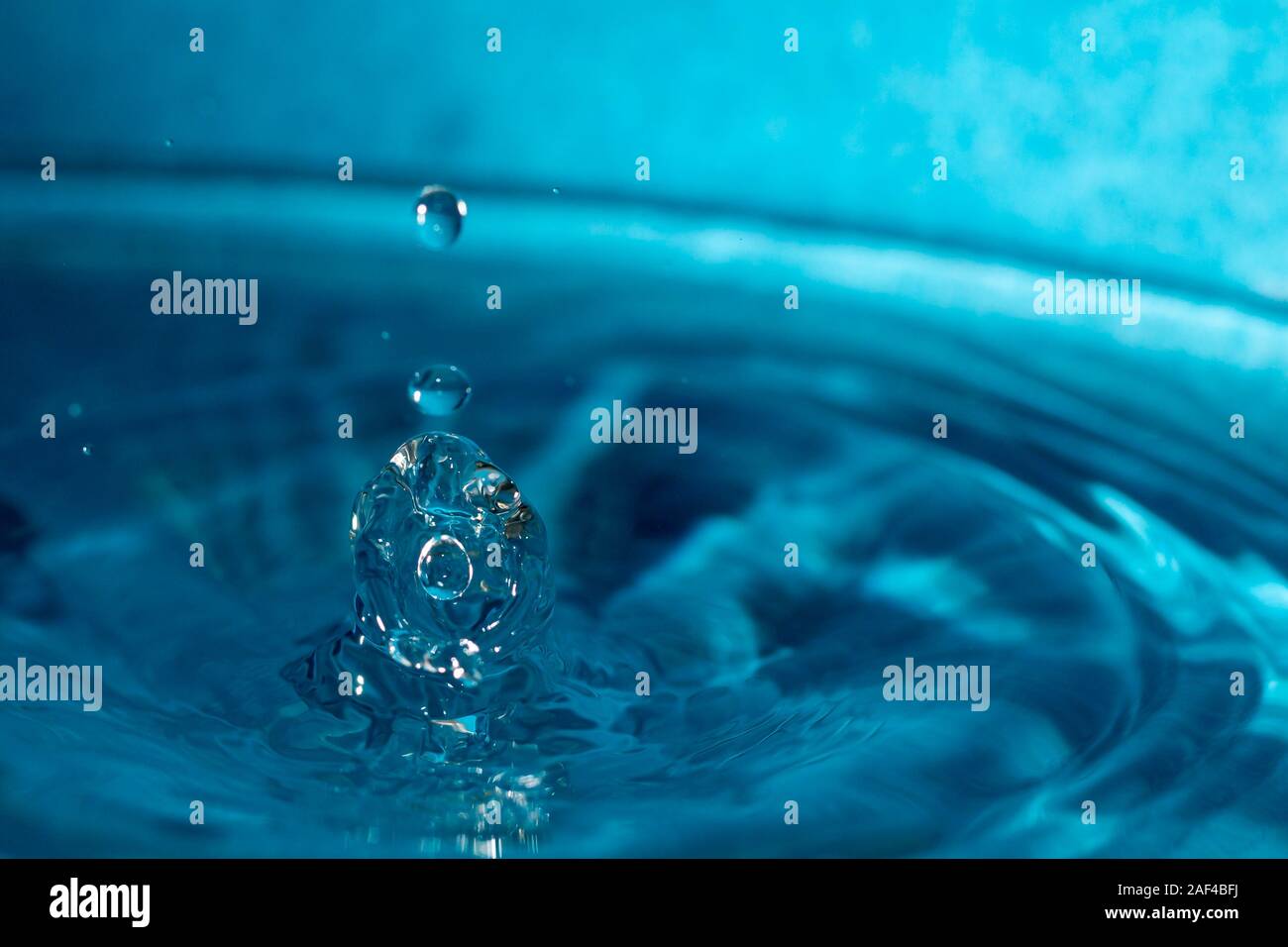 Wassertropfen spritzen in einem blauen Glas Stockfoto