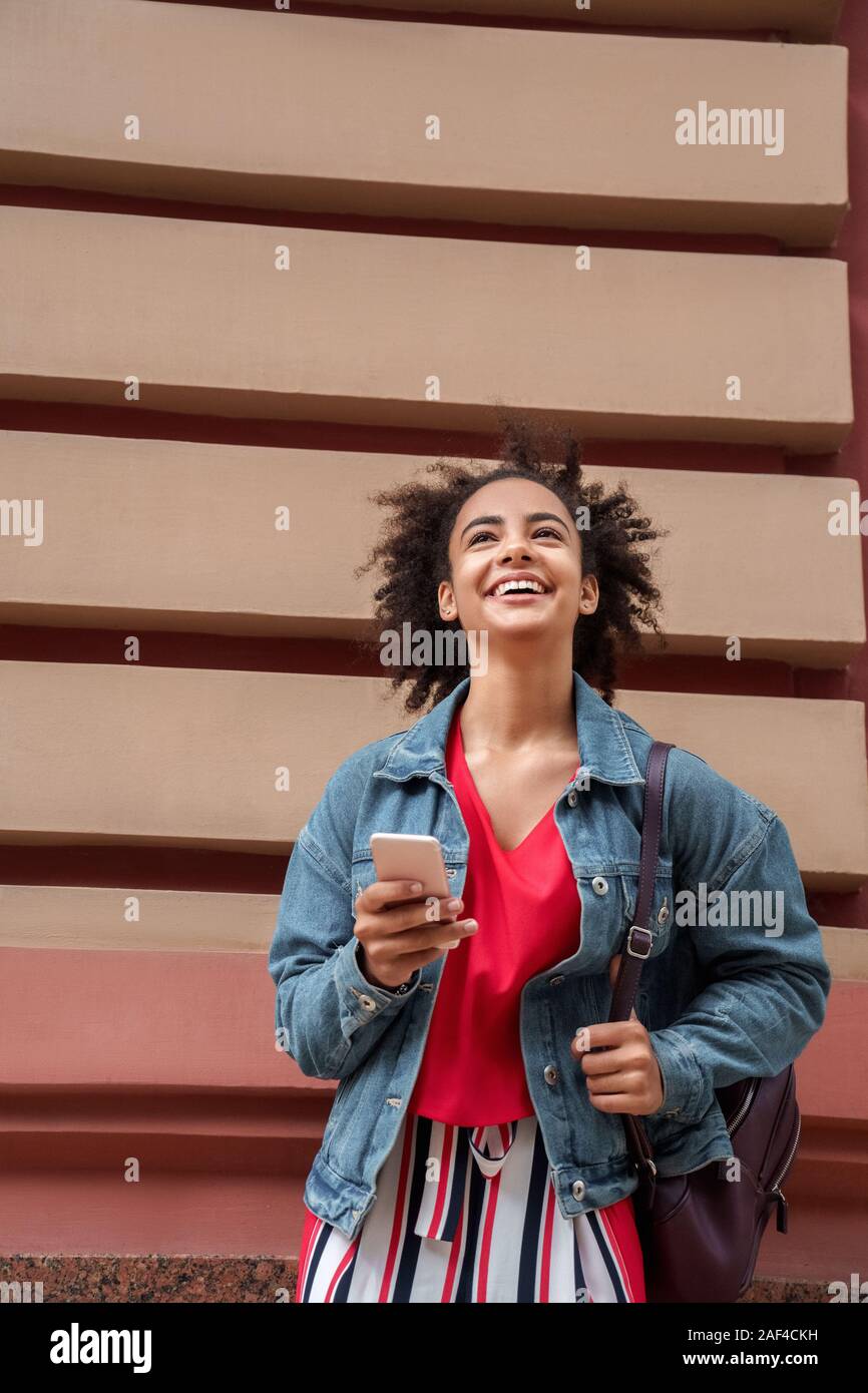 Freizeitaktivitäten im Freien. Junge Mädchen in Jean jacket stehen auf der Straße Hintergrund surfen smartphone Lachen heiter Stockfoto