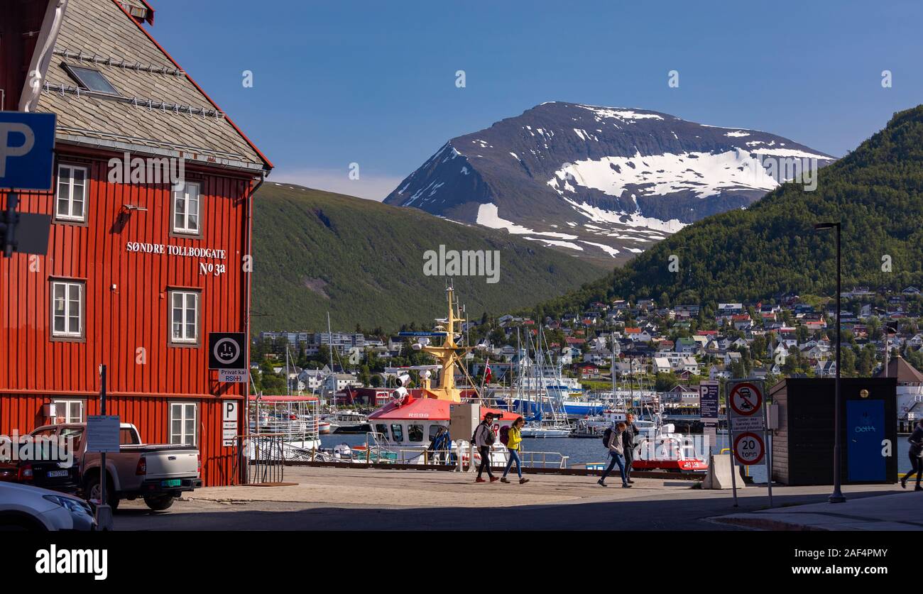 TROMSØ, NORWEGEN - Menschen zu Fuß am Hafen mit Bergen in der Ferne. Stockfoto