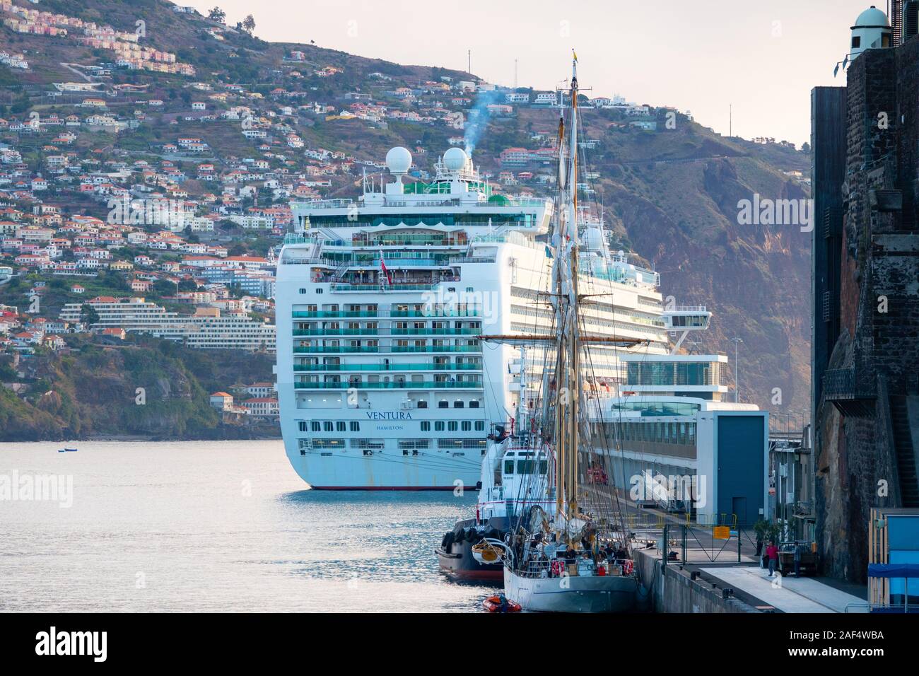 Die P&O Cruises Schiff, Ventura, angedockt im Hafen von Funchal, Madeira an einem bewölkten Morgen mit Hang und Gebäude im Hintergrund. Stockfoto