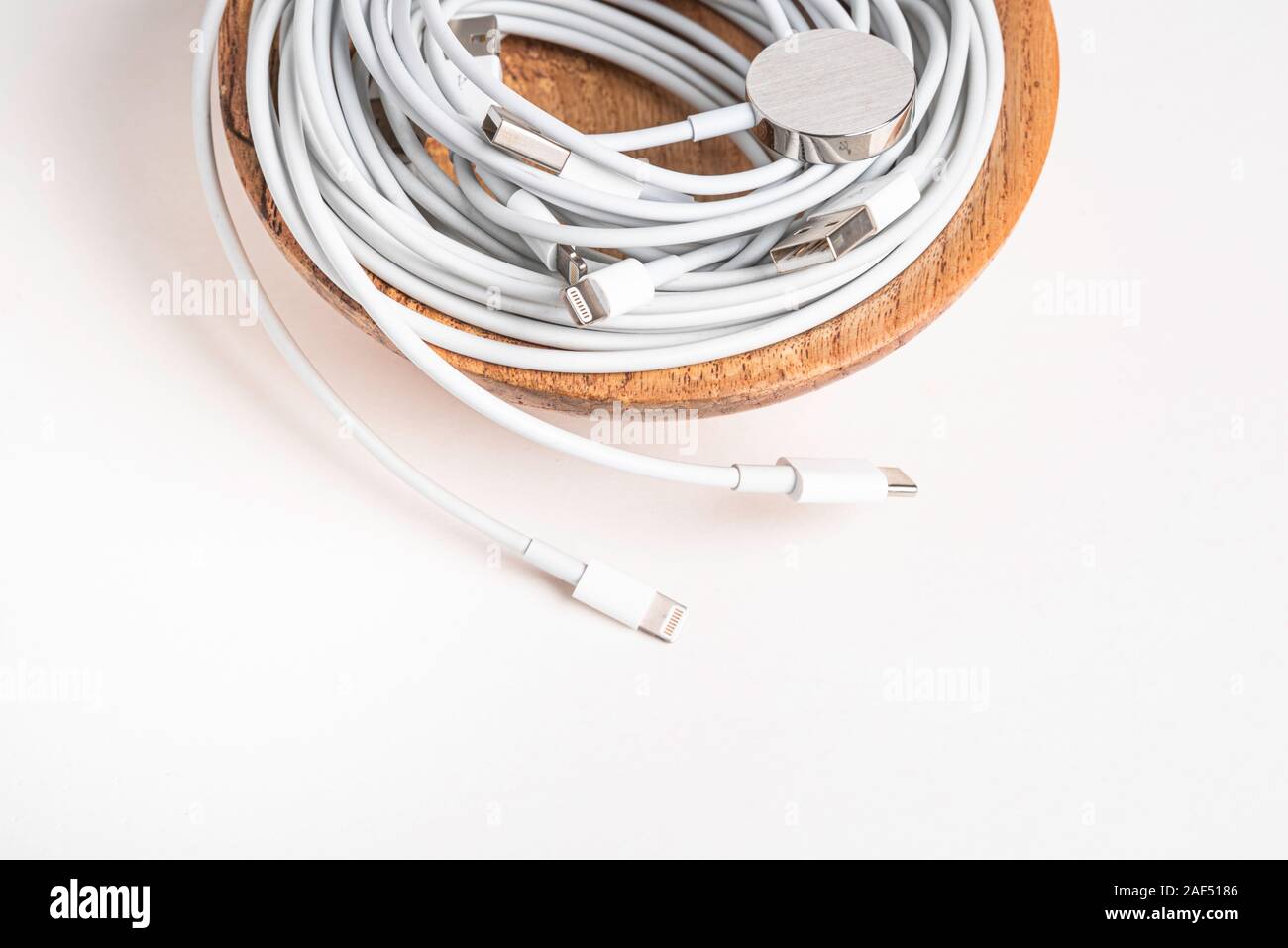 Mehrere weiße Apple Power Kabel und Stecker in eine hölzerne Schüssel auf weißem Hintergrund. Stockfoto