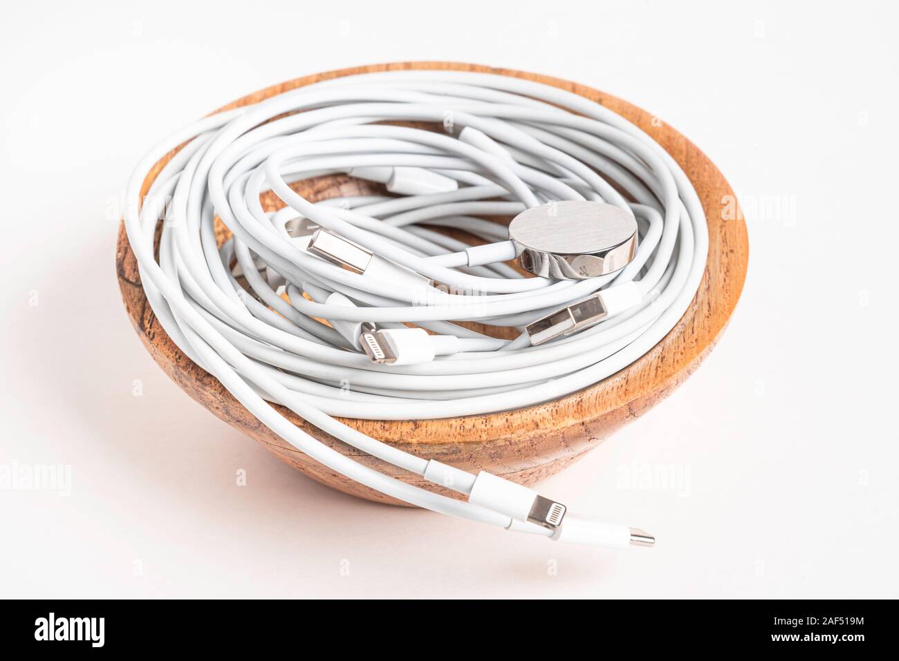 Mehrere weiße Apple Power Kabel und Stecker in eine hölzerne Schüssel auf weißem Hintergrund. Stockfoto