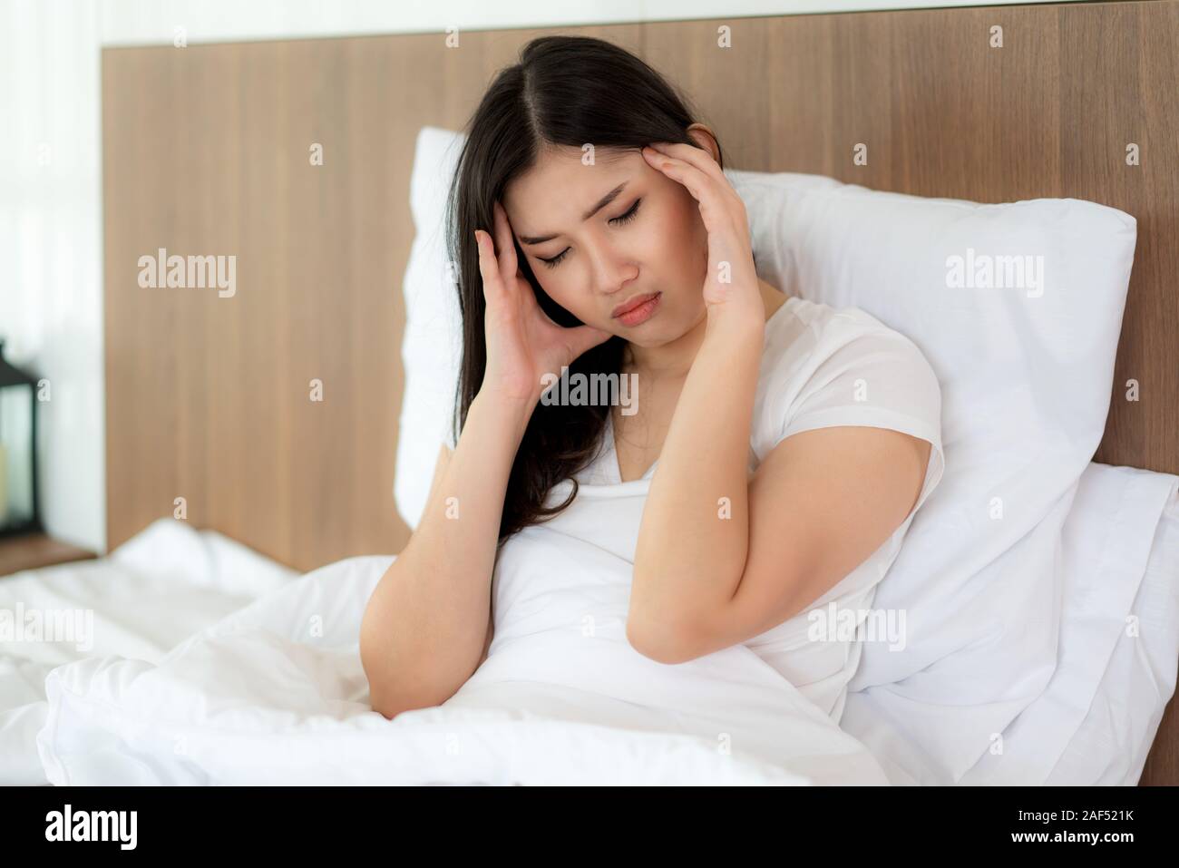 Attraktive junge asiatische Frau Aufwachen auf ihrem Bett ihre Hand von Kopfschmerzen und Suchen unglücklich und Gefühl Kopfschmerzen/Migräne/Stress/krank. Stockfoto