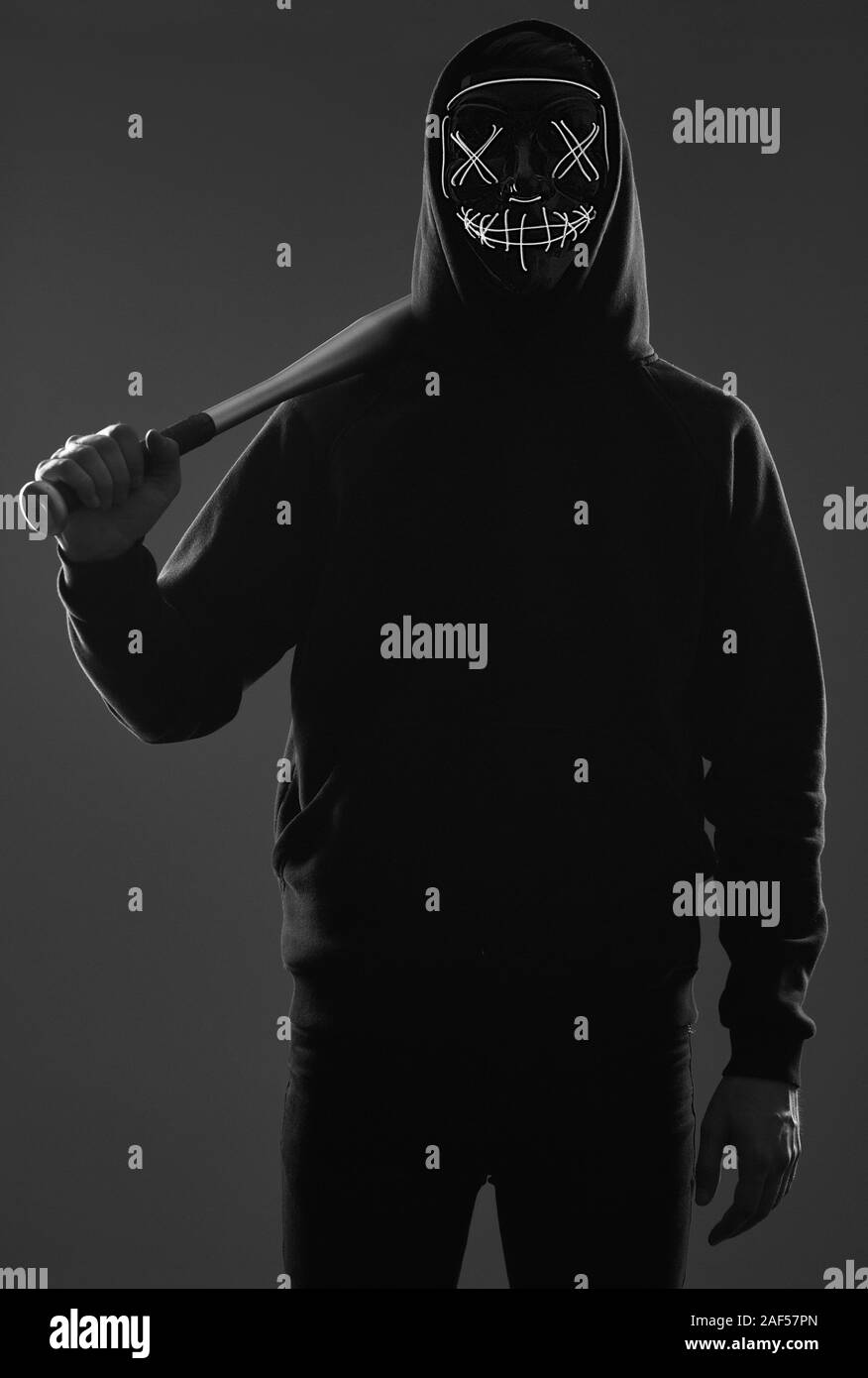 Porträt eines anonymen kriminellen Mann mit Baseballschläger in einer schwarzen Kapuze sein Gesicht hinter einer Maske. Studio gedreht. Stockfoto