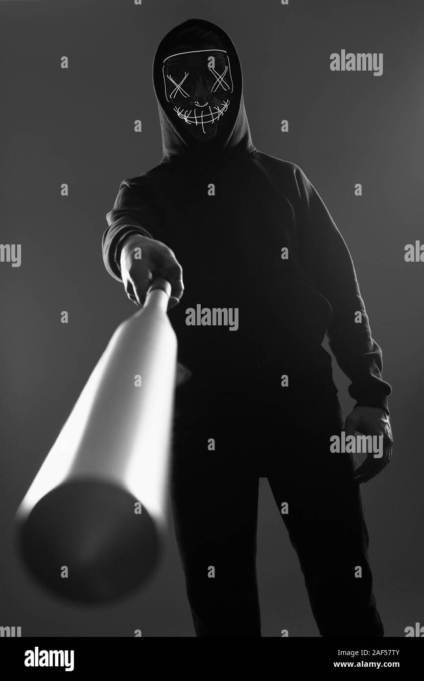 Porträt eines anonymen kriminellen Mann mit Baseballschläger in einer schwarzen Kapuze sein Gesicht hinter einer Maske. Unterer Winkel Stockfoto