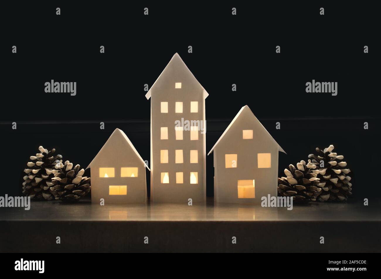 Winterlandschaft mit kleinen Häusern aus Papier beleuchtete innen und mit Tannenzapfen Stockfoto