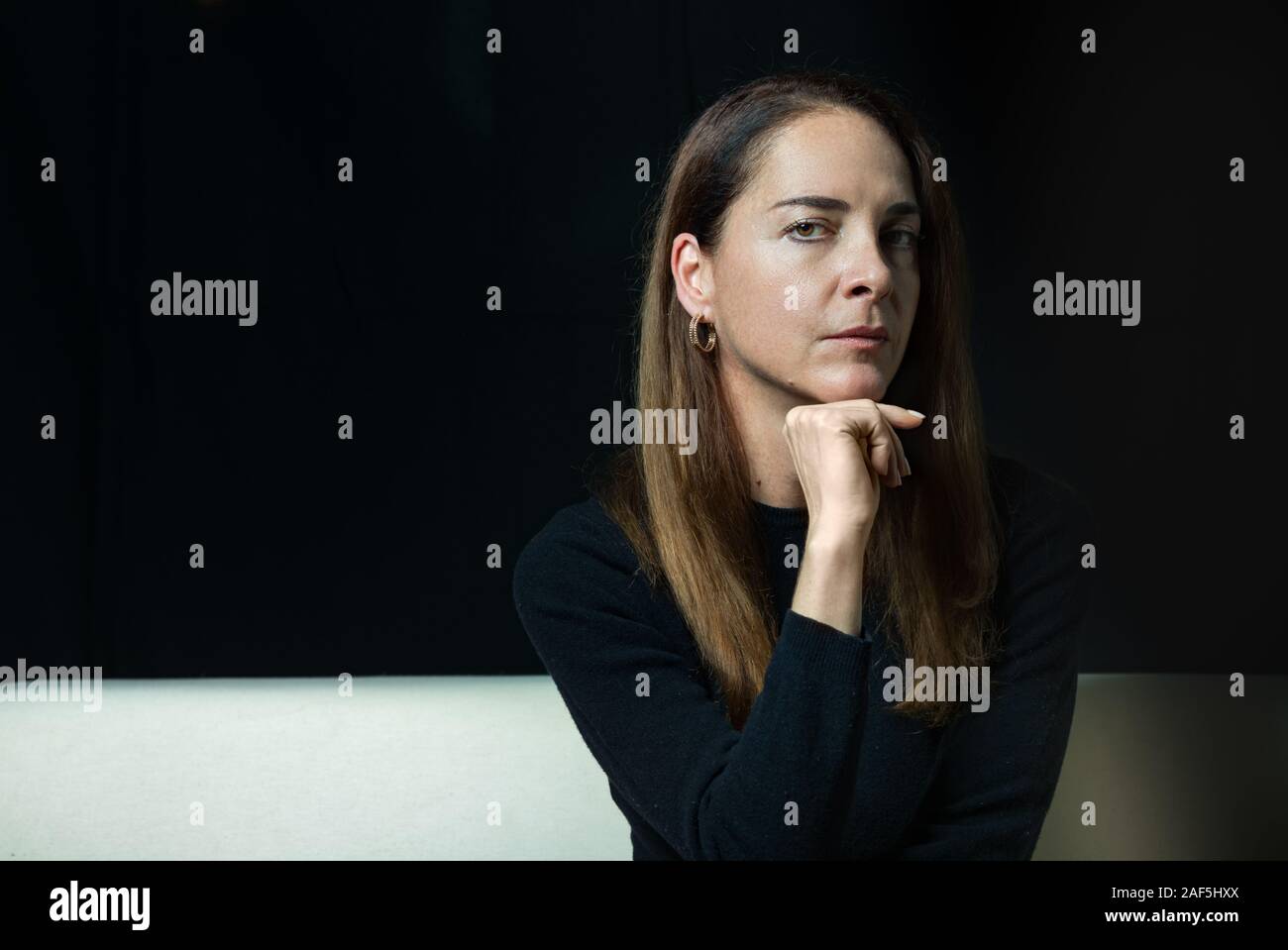 Reife Frau von 45 - 50 Jahren, ernst, nachdenklich, die Kamera mit der Hand am Kinn über schwarzen Hintergrund. Stockfoto
