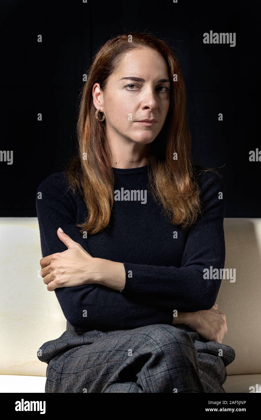 Reife Frau von 45 - 50 Jahren, ernst, nachdenklich, Kamera mit gekreuzten Armen über schwarzen Hintergrund. Stockfoto