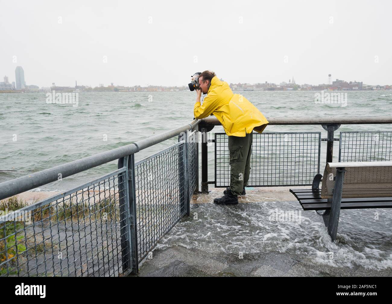 Ein Mann, der während des Hurrikans Sandy Fotos von der Sturmflut des East River gemacht hat, während das Wasser um ihn herum überflutete. Stockfoto