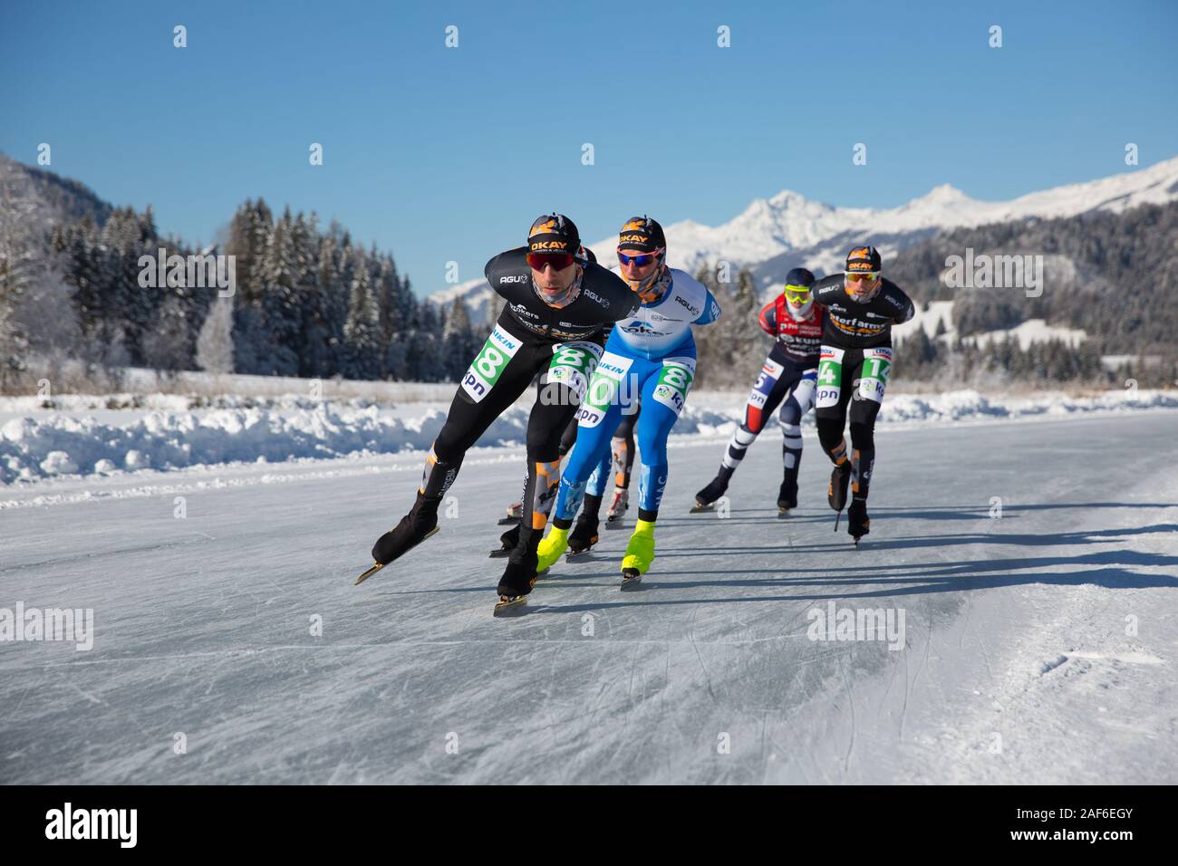Schlittschuhlaufen auf dem See, in einem schönen Winterlandschaft. Gruppe von Männern Meisterschaft Marathon Ice Speed-Skating auf Natureis, Weissensee, Österreich Stockfoto