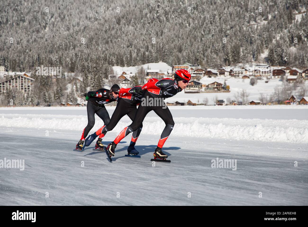 Schlittschuhlaufen auf dem See, in einem schönen Winterlandschaft. Gruppe von Männern Meisterschaft Marathon Ice Speed-Skating auf Natureis, Weissensee, Österreich Stockfoto